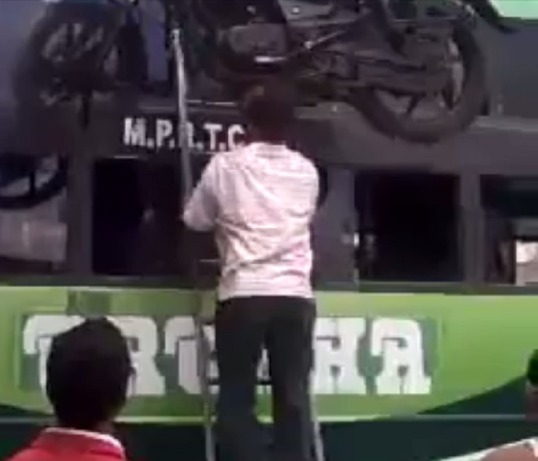 Ez az indiai férfi a fejével viszi fel egy létrán a motort egy kamion tetejére