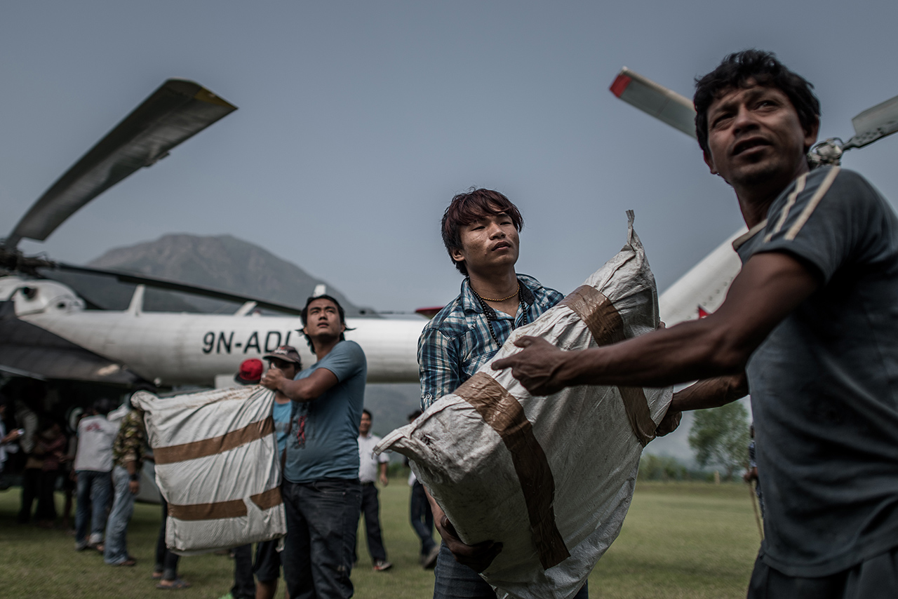 Workers load relief supplies in a helicopter for the World Food Programme (WFP) in Deurali village of Nepal's Gorkha district on May 6, 2015. The earthquake that struck Nepal on April 25, 2015, killed more 7,600 people and injured another 16, 390 across the country, according to the Nepal Emergency Operation Centre. AFP PHOTO/Philippe Lopez