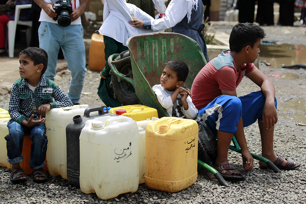 Young Yemenis wait to fill jerrycans with water from a public tap amid an acute shortage of water supply to houses in the capital Sanaa, on May 9, 2015. The Saudi-led coalition bombed the Yemeni capital's airport and the Shiite rebels' northern stronghold just hours after proposing a humanitarian ceasefire to start next week. AFP PHOTO / MOHAMMED HUWAIS