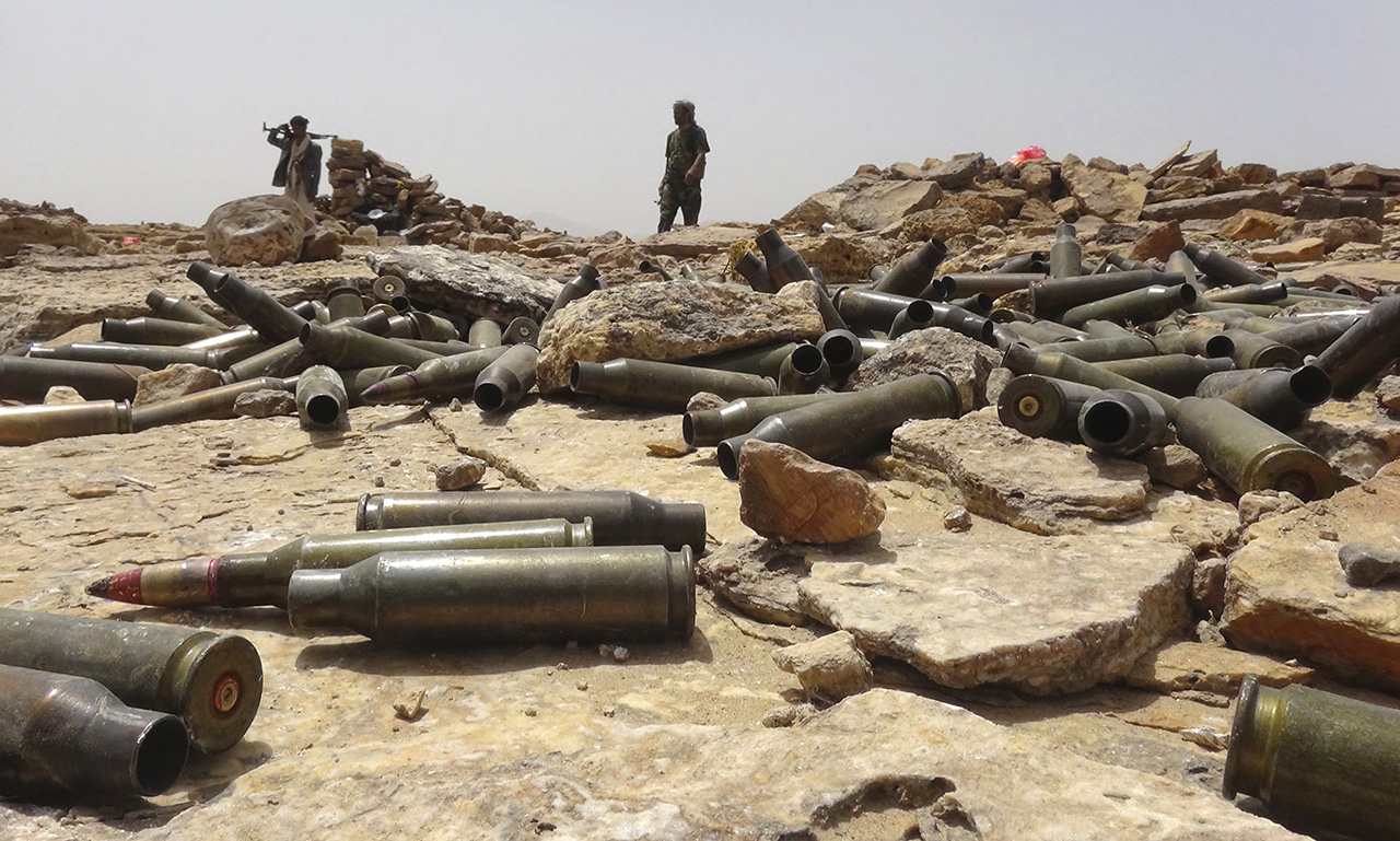 Armed Yemeni tribesman from the Popular Resistance Committees supporting forces loyal to Yemen's Saudi-backed fugitive President Abedrabbo Mansour Hadi stand behind piles of artillery shells as they continue to battle Shiite Huthi rebels in the area of Sirwah, in the west of Marib province, east of the capital, Sanaa, on May 10, 2015. AFP PHOTO / STR