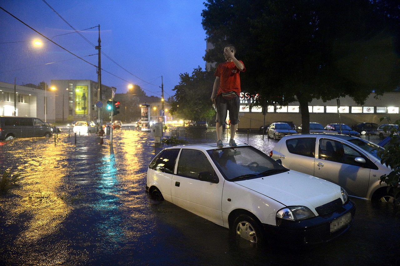 Egy férfi áll az elakadt autója tetején a vízzel elöntött XIII. kerületi Béke térnél (Fotó: Bruzák Noémi / MTI)
