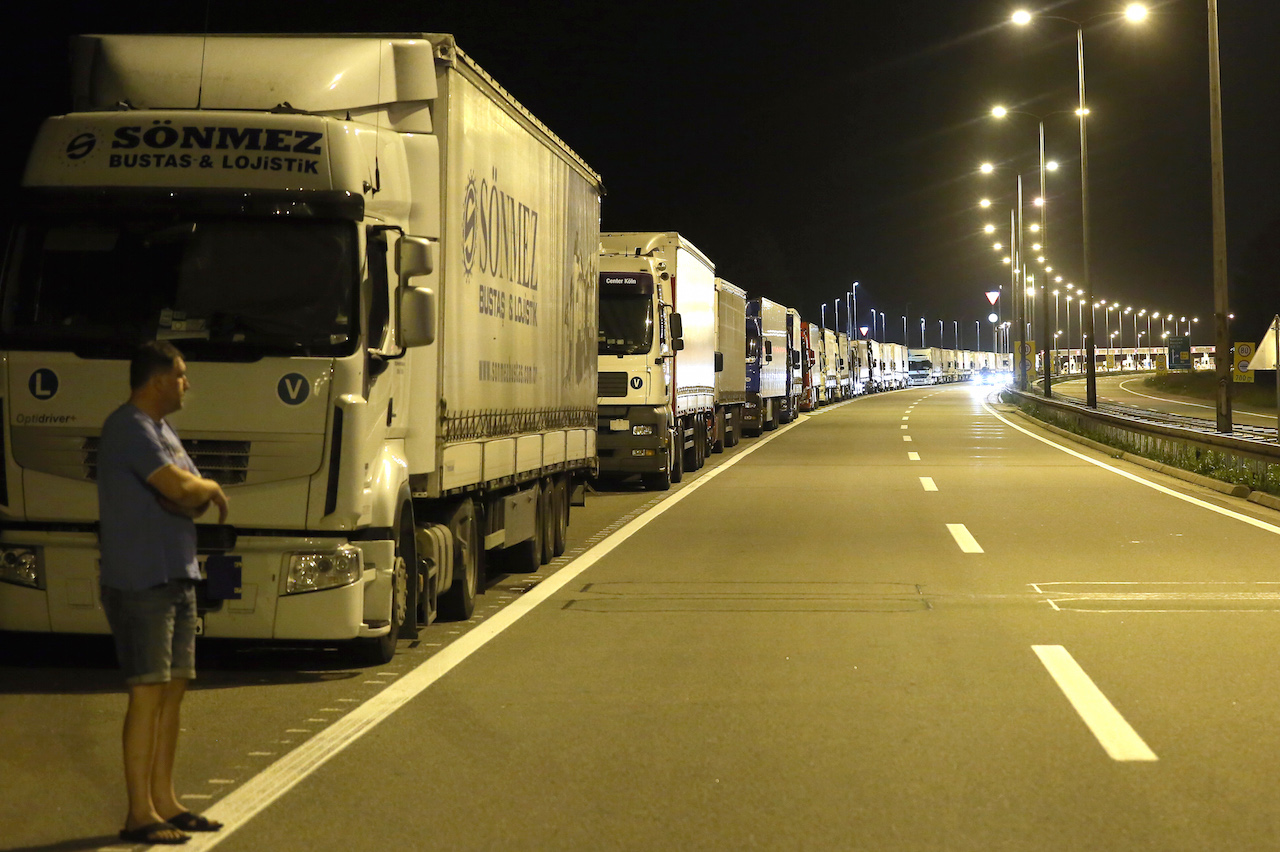A truck driver stands in front of his vehicle at the highway on September 23, 2015, near the Batrovci border crossing between Serbia and Croatia. On Wednesday evening, Serbia banned the entry into its territory of trucks registered in Croatia and Croatian products as a counter measure against Croatia's decision to block truck traffic with Serbia. On Monday, Croatia blocked trucks coming from Serbia in a bid to pressure Belgrade to redirect the influx of migrants and refugees towards Hungary and Romania.  AFP PHOTO / OLIVER BUNIC