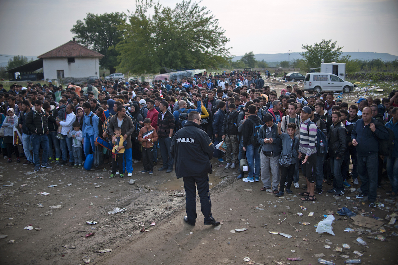 TOPSHOTS Macedonian police officers control a crowd of migrants and refugees as they prepare to enter a camp after crossing the Greek border into Macedonia near Gevgelija on September 23, 2015. European Union leaders hold an emergency migration summit on September 23 amid a growing east-west split after ministers forced through a controversial deal to relocate 120,000 refugees. AFP PHOTO / NIKOLAY DOYCHINOV