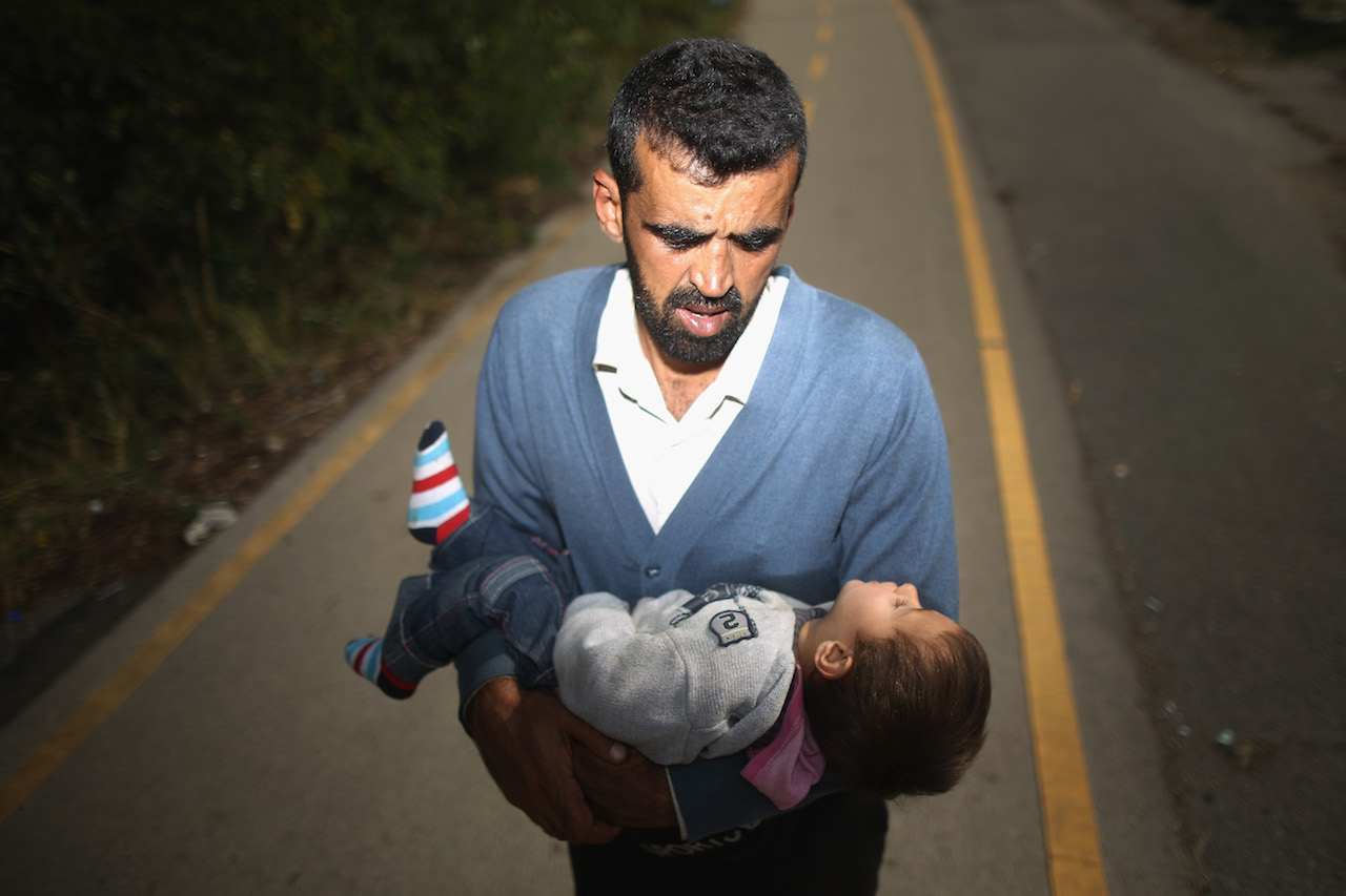 HEGYESHALOM, HUNGARY - SEPTEMBER 23:  A father who arrived by train at Hegyeshalom on the Hungarian and Austrian border, carries his dehydrated son the four kilometres ito the Austrian border. The young boy was treated by volunteers of the Hungarian Red Cross and they continued their journey into Austria on September 23, 2015 in Hegyeshalom, Hungary. Thousands of migrants have arrived in Austria with more en-route from Hungary, Croatia and Slovenia.  EU leaders are attending an extraordinary summit on today to try and solve the crisis.  (Photo by Christopher Furlong/Getty Images)