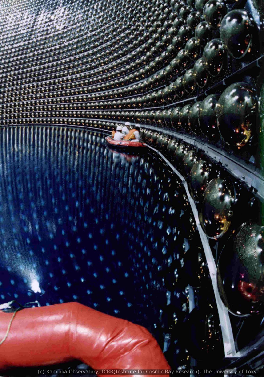 A félig leeresztett Superkamiokande tartályában csónakázó mérnökök, amint a fénymérő fotoelektromos érzékelőket ellenőrzik.