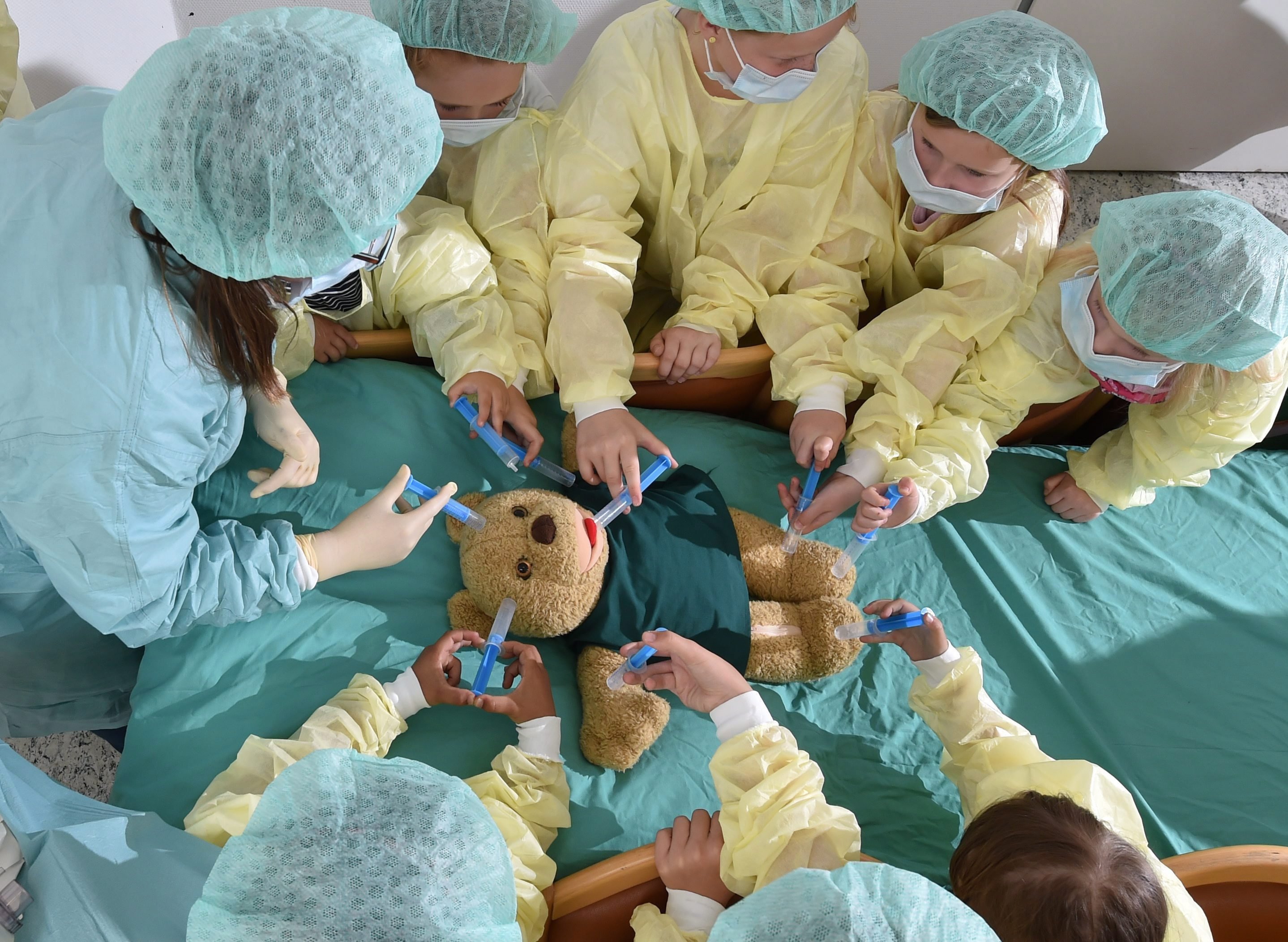 Kislányok egy plüssállat orvosi ellátását mímelik egy orvostanhallgató (balra) vezetésével a közép-németországi Halle (Saale) egyetemi kórházában 2016. május 23-án.