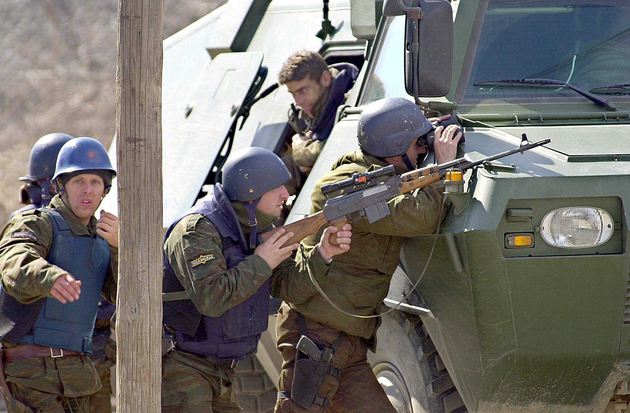 Macedón rendőrök egy páncélos mögött húzódnak fedezékbe, mert az albán gerillák tűz alá vették a csapatukat (2001-es fotó / AFP PHOTO ERIC FEFERBERG)