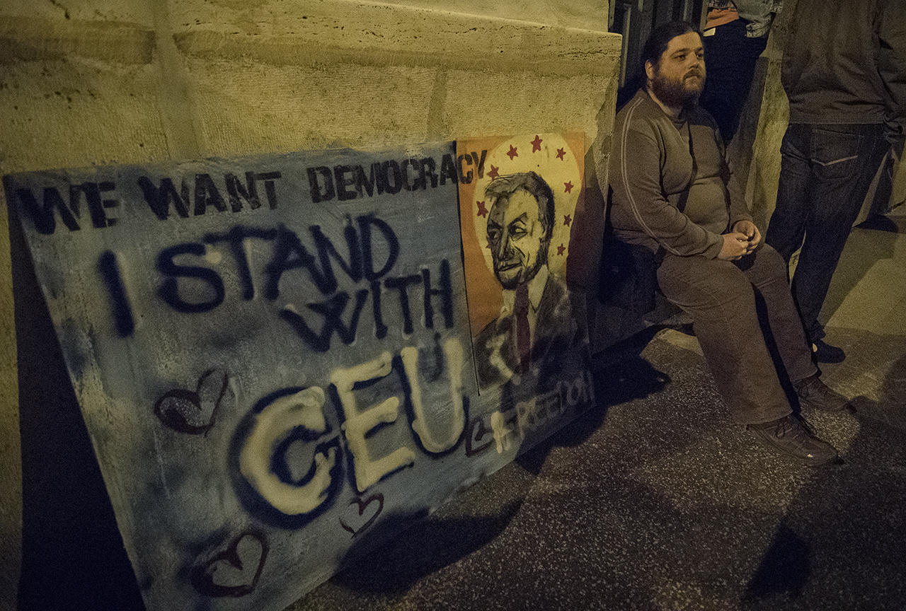 A bűnözők ismertetőjelét, a „graffitit” idéző táblával provokálja a kormányt egy CEU-párti ügynöktüntető