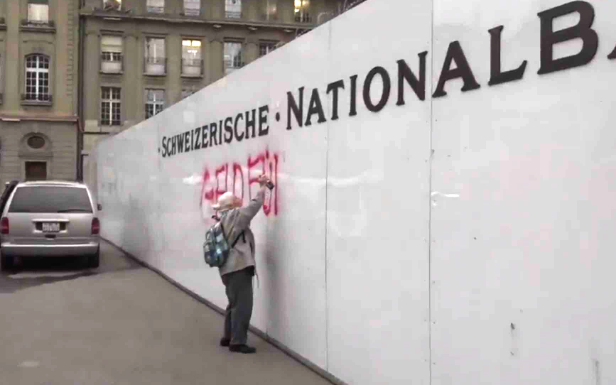 Bevitték a rendőrök a 86 éves nénit, aki szétgraffitizte a fegyverbizniszben utazó svájci jegybank falát