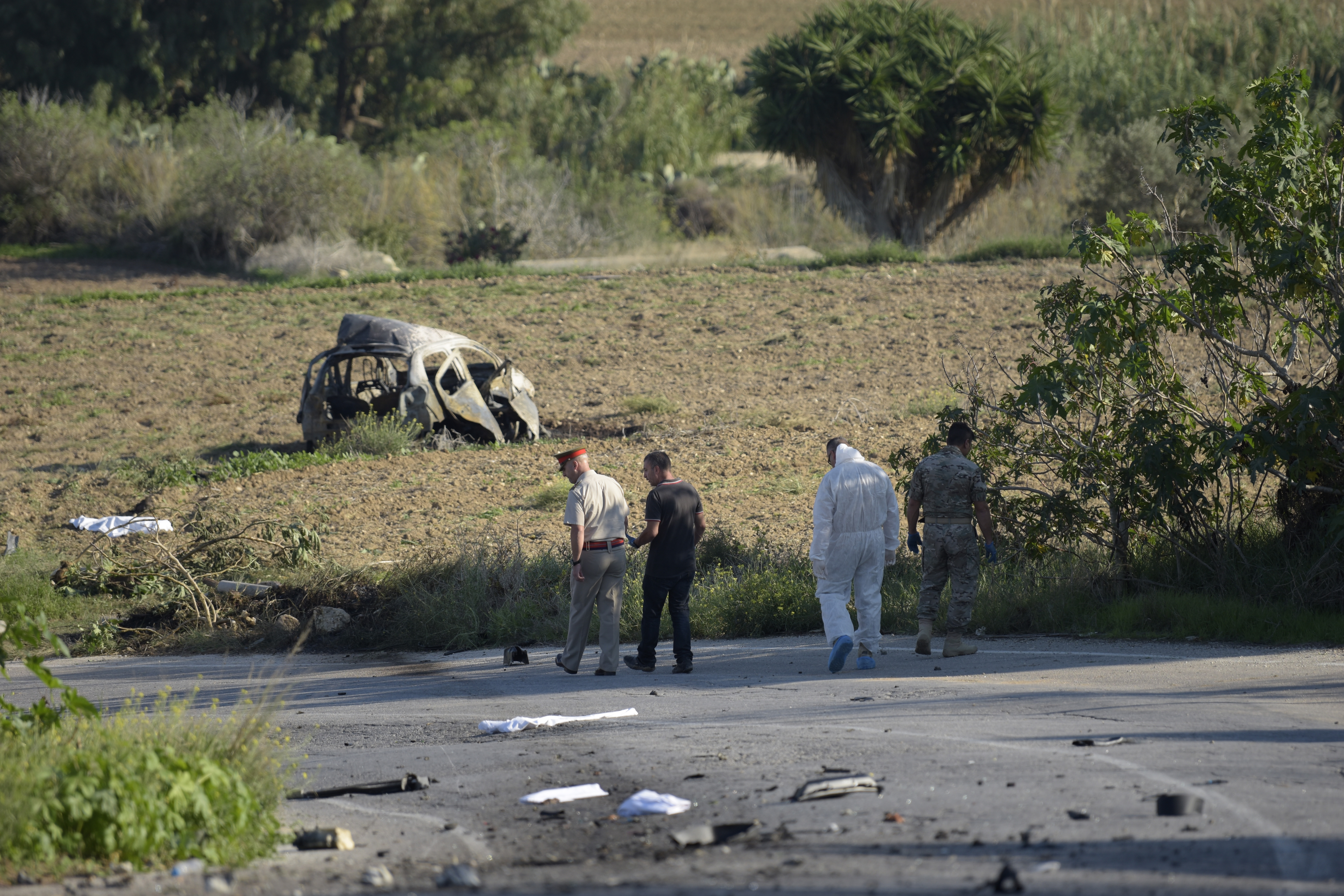 Rendőrök és helyszínelők Daphne Caruana Galizia oknyomozó újságíró felrobbantott autójánál 2017. október 16-án.