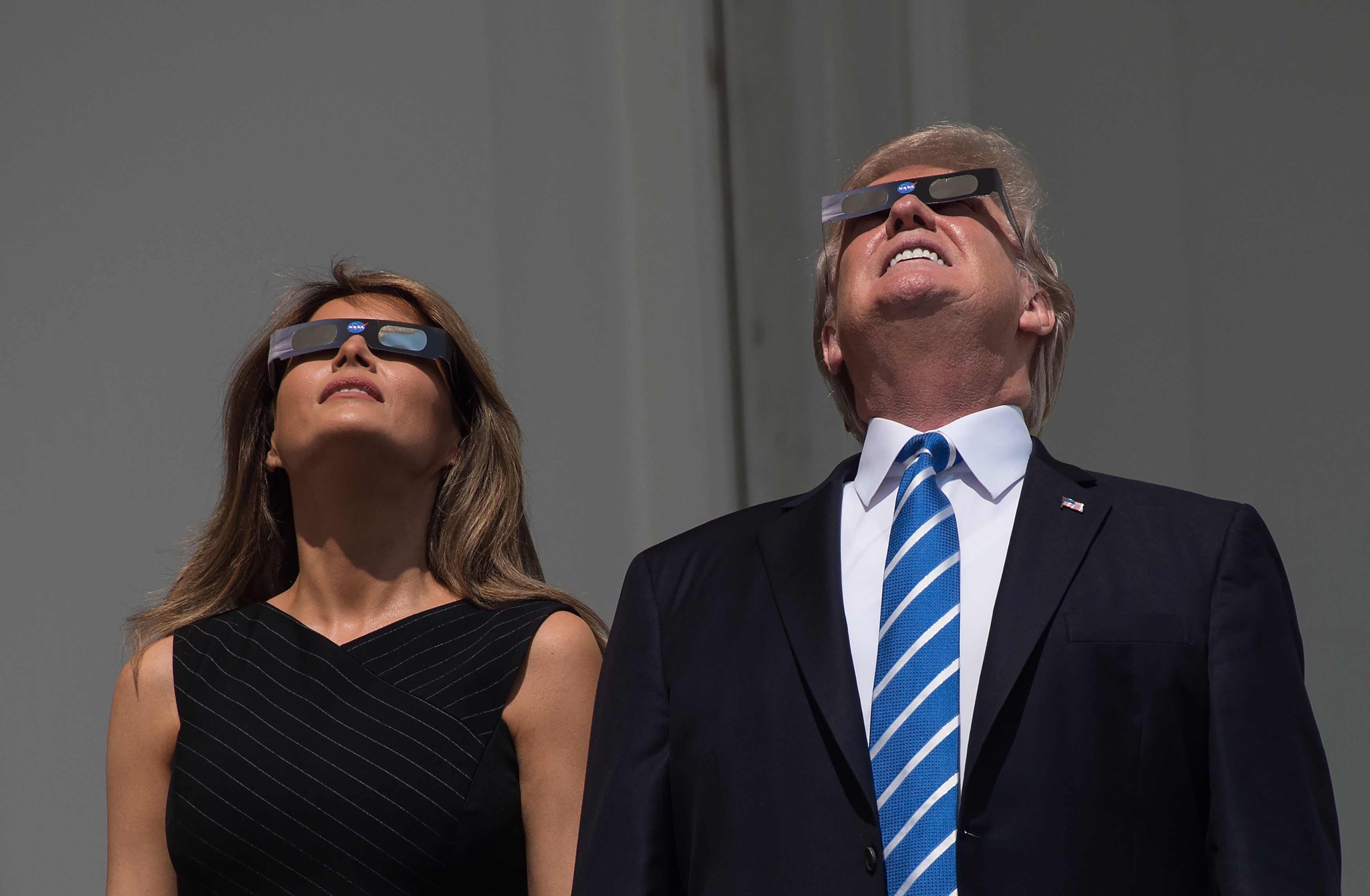 US President Donald Trump and First Lady Melania Trump look up at the partial solar eclipse from the balcony of the White House in Washington, DC, on August 21, 2017. / AFP PHOTO / NICHOLAS KAMM