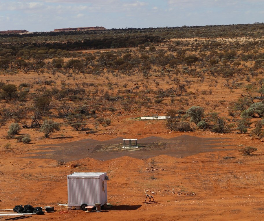Két EDGES antenna a sivatagban. A tényleges antennák a pingpongasztal jellegű szerkezetek, a nagyobb fémháló (elöl), illetve fémlapok (hátul) csak a szigetelést adják a föld felől.