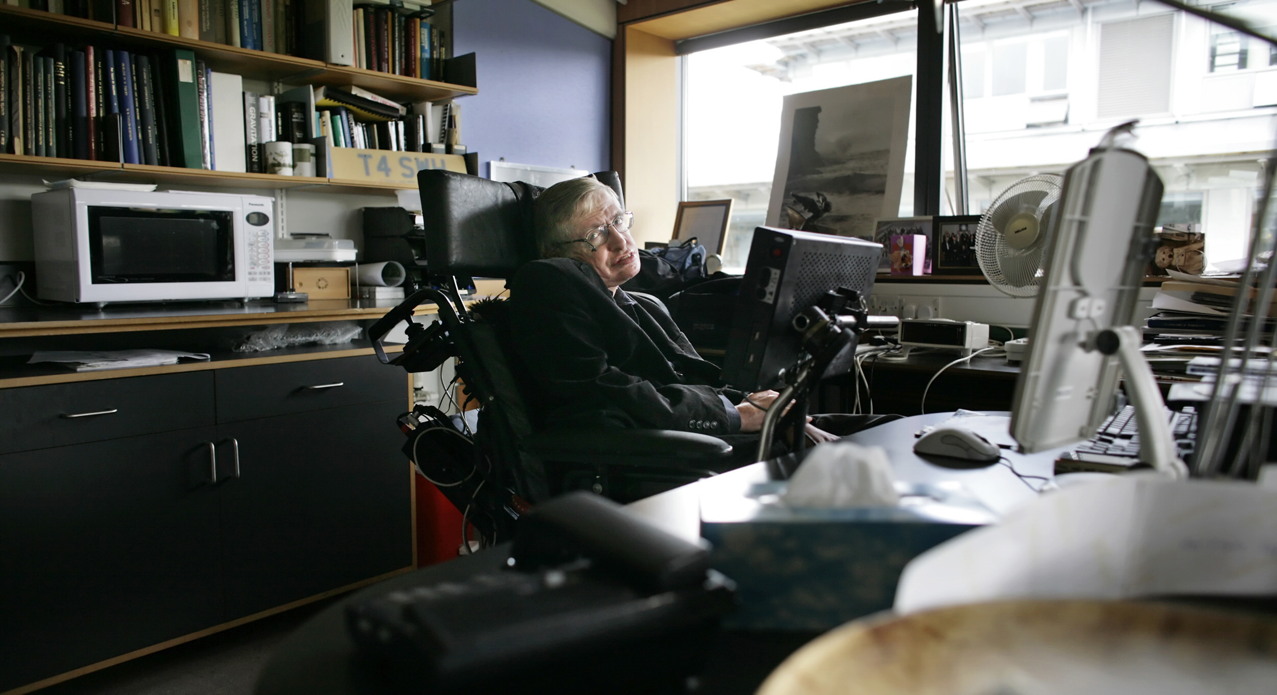 Stephen Hawking Cambridge-i irodájában, a Matematikai Tudományok Központjában, mikrohullámú sütővel a háttérben