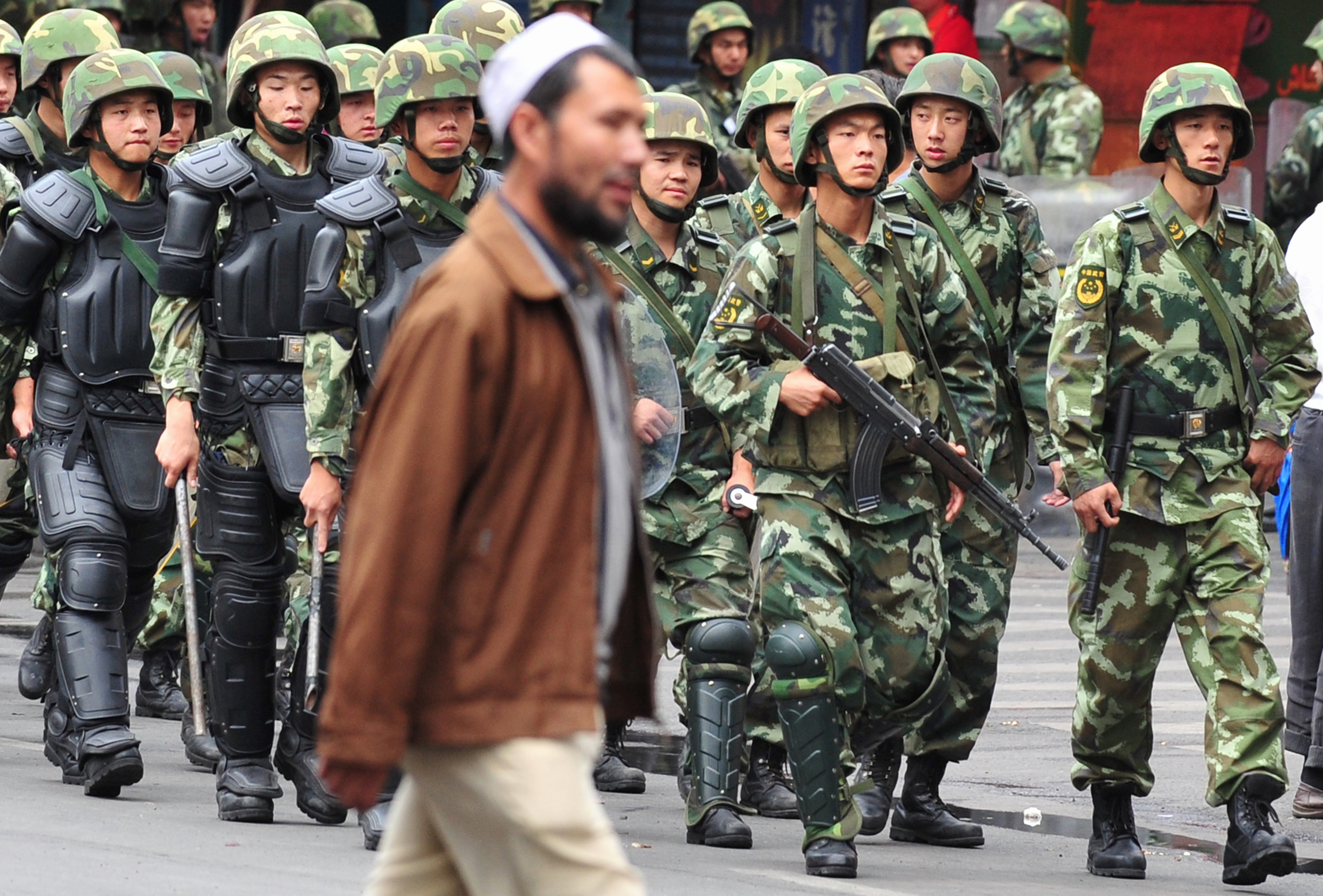 Ujgur férfi és kínai katonák Hszincsiangban