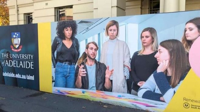 Némán figyelő nők gyűrűjében magyarázó férfit ábrázoló plakát miatt háborodtak fel Ausztráliában