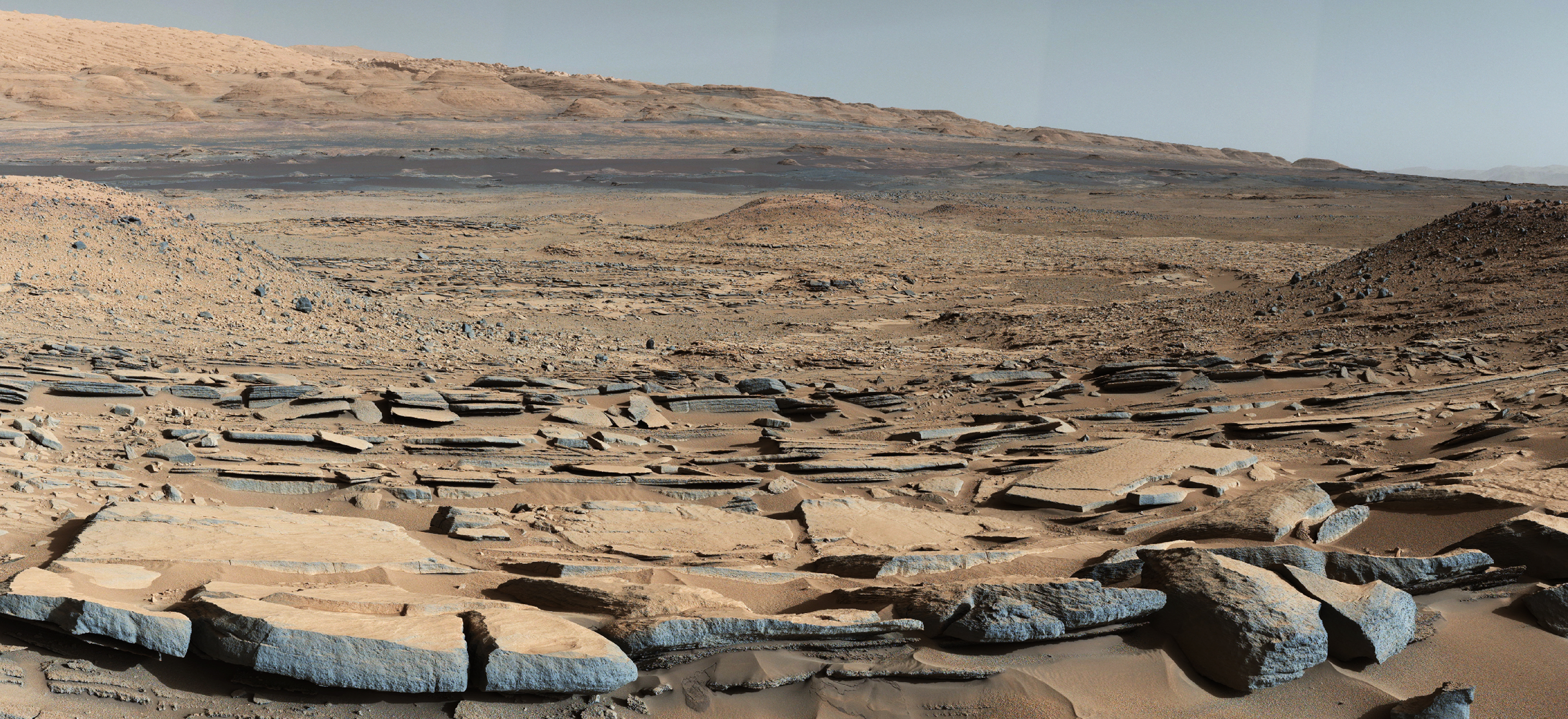 A Curiosity a Kimberley-képződményben készített fotójának előterében látható kőzetrétegek a Sharp-hegy felé való dőlése arra utal, hogy korábban egy vízzel teli medence volt a hegy helyén (2015. október 9.)