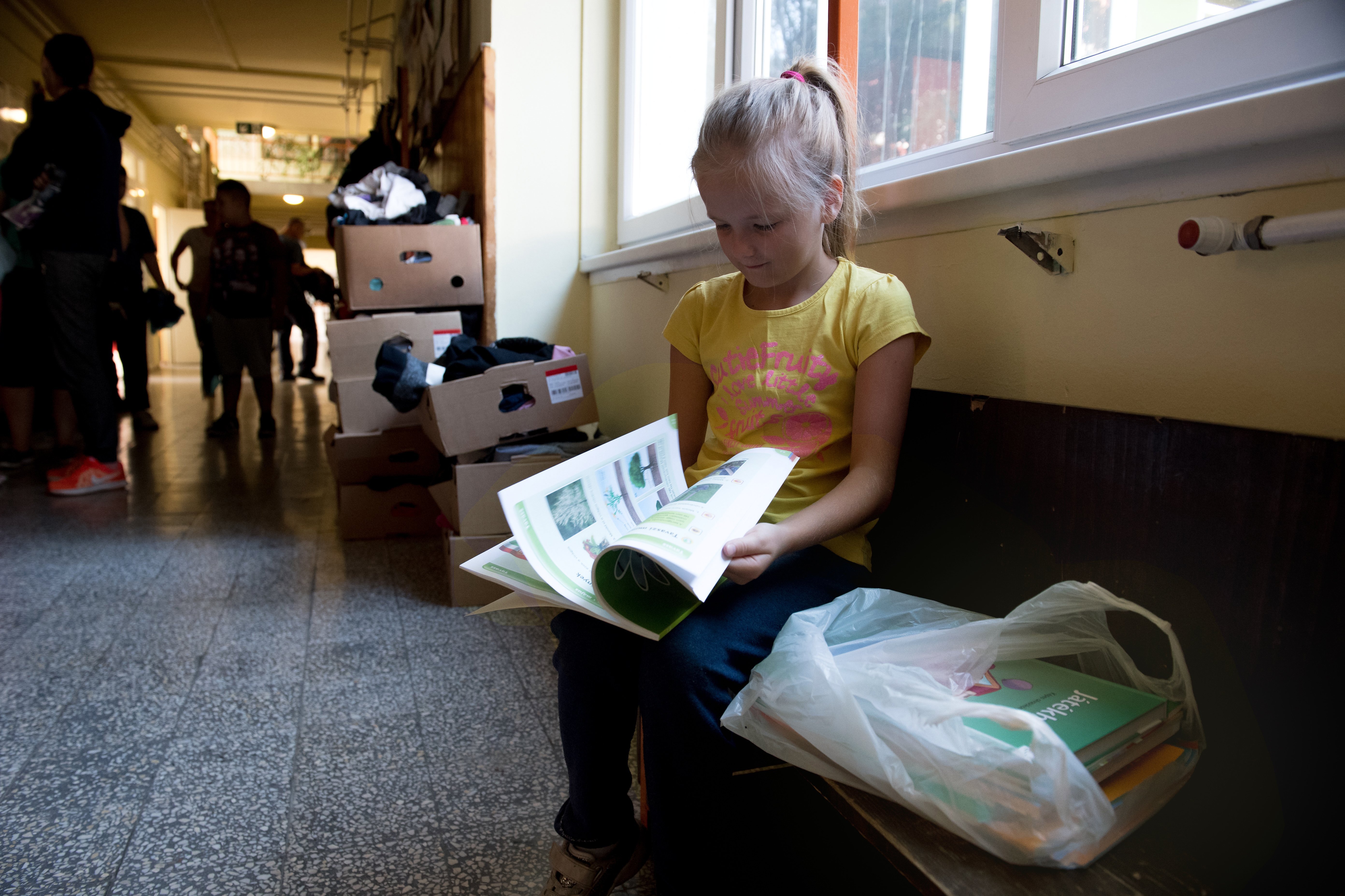 Egy kislány nézegeti az egyik új tankönyvét a Gyáli Bartók Béla Általános Iskolában 2018. augusztus 29-én