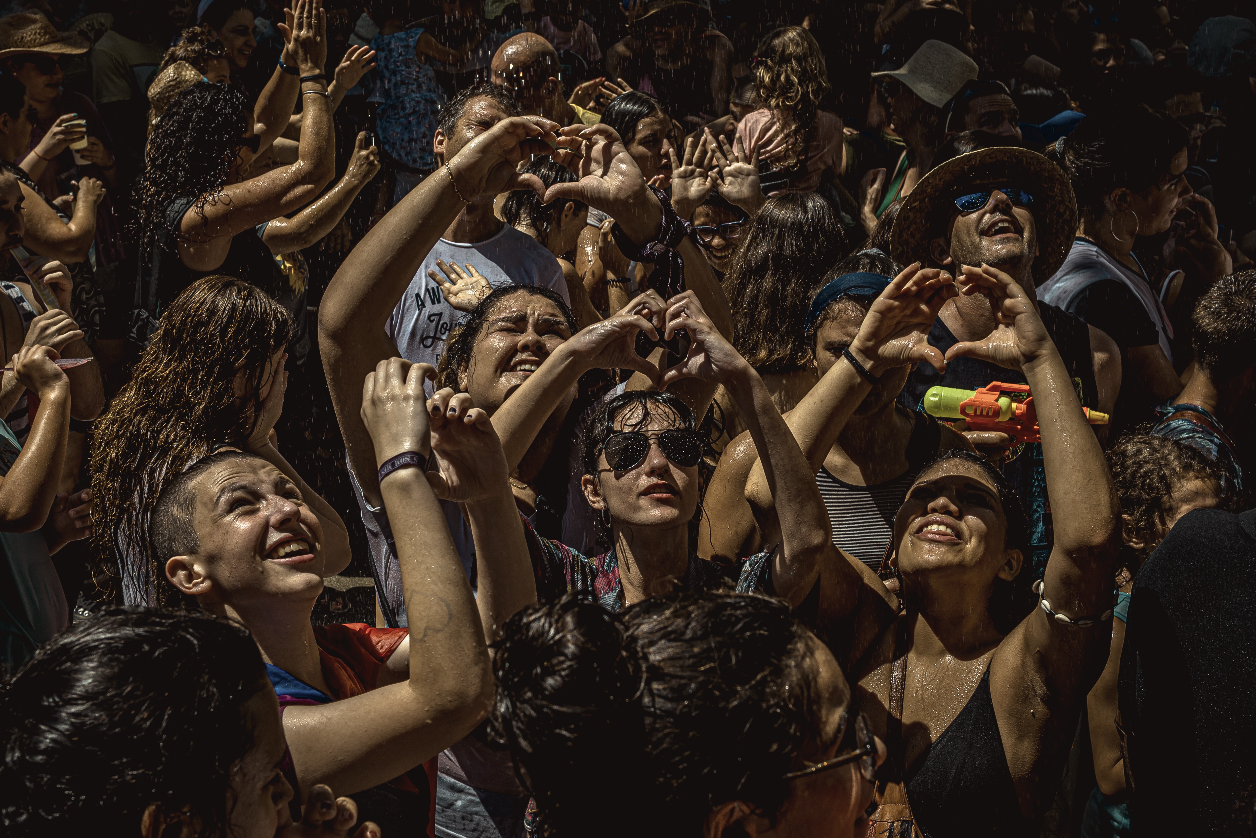 Spanyol utcai fesztiválozók formálnak szívet a kezükkel, miután egy erkélyről vizet locsoltak rájuk
