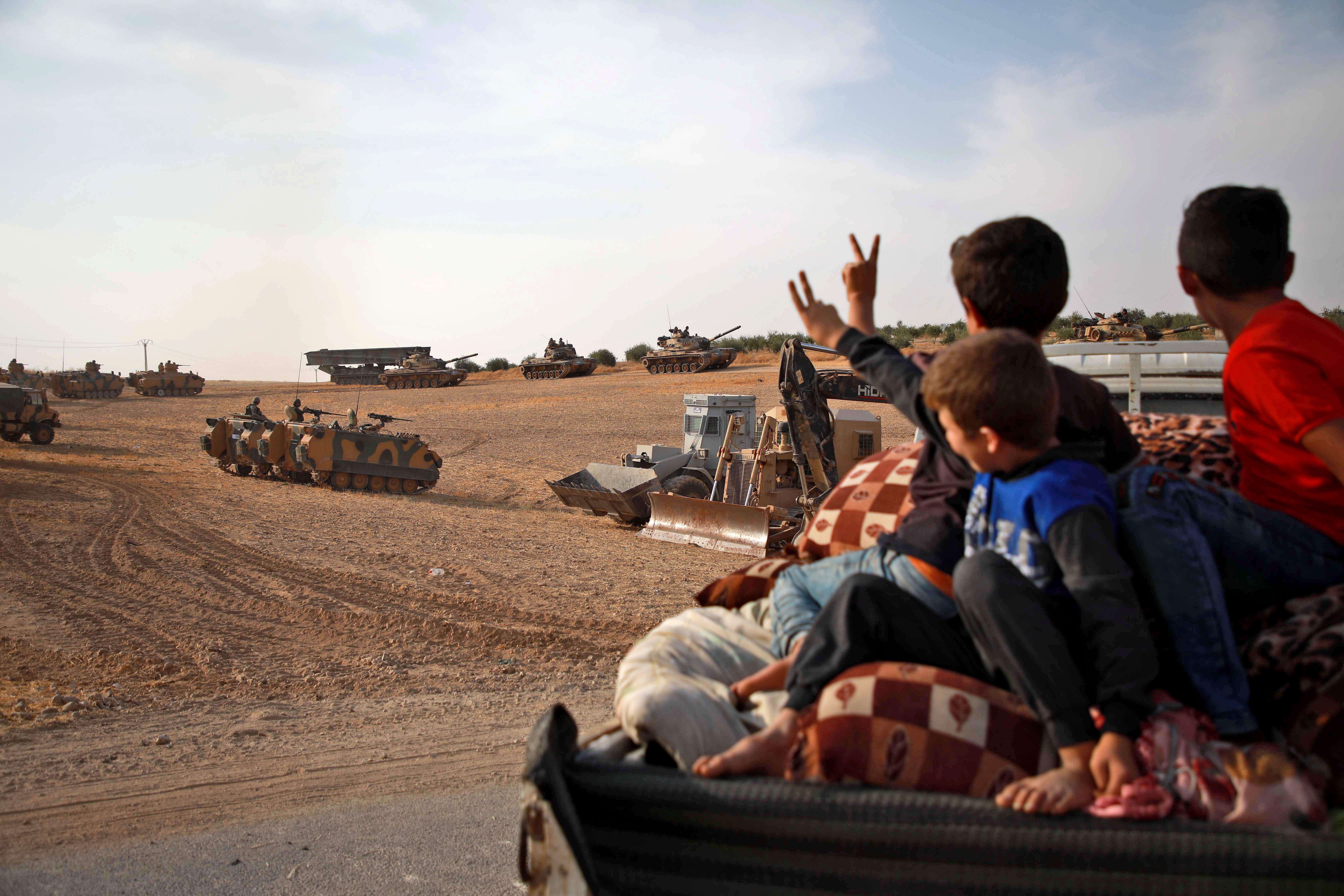 Szíriai arab gyerekek integetnek a török hadsereg harcjárművei felé.