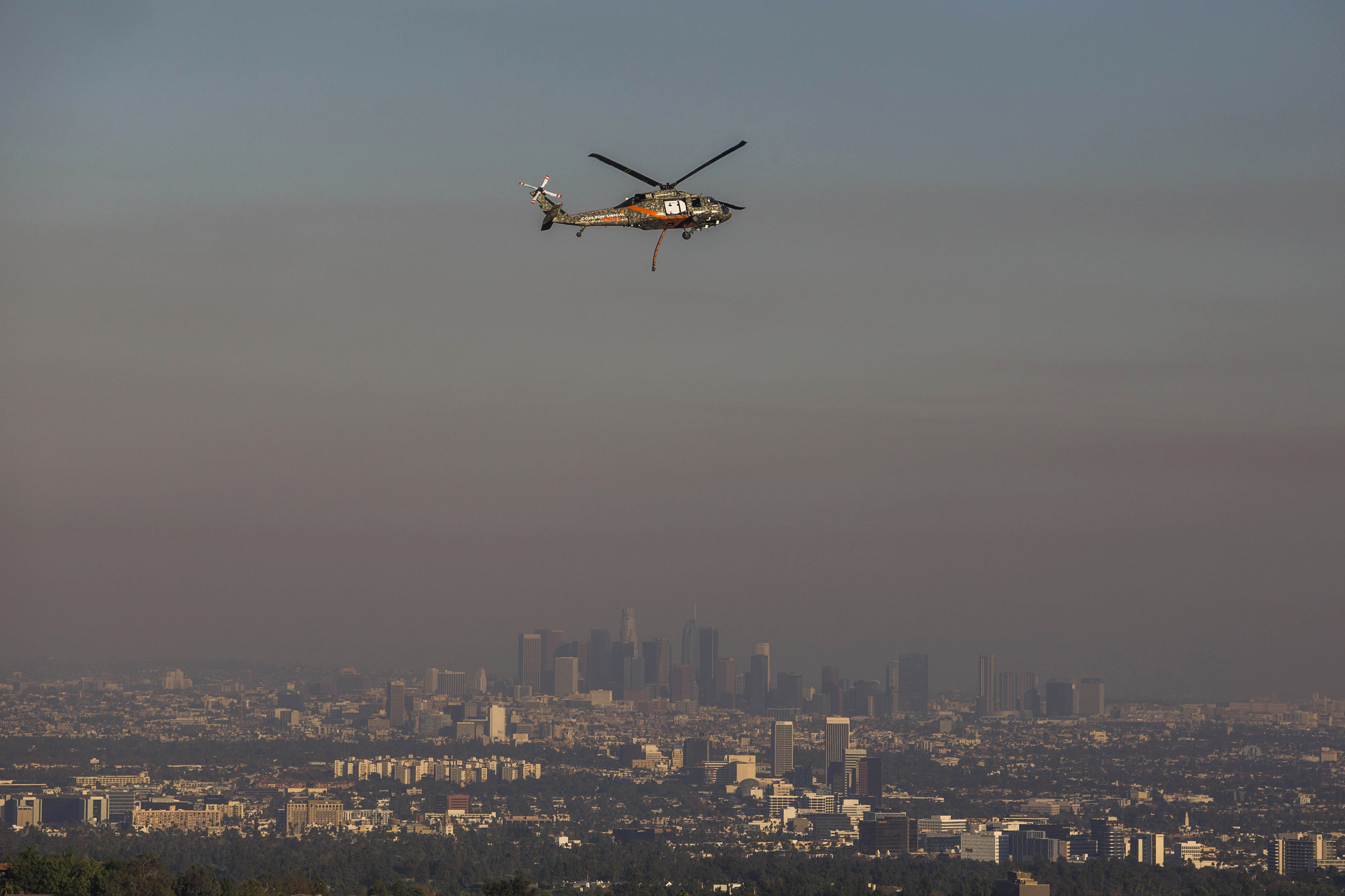 A Getty Múzeumot fenyegető erdőtűz füstje és egy mentőhelikopter Los Angeles fölött október 28-án
