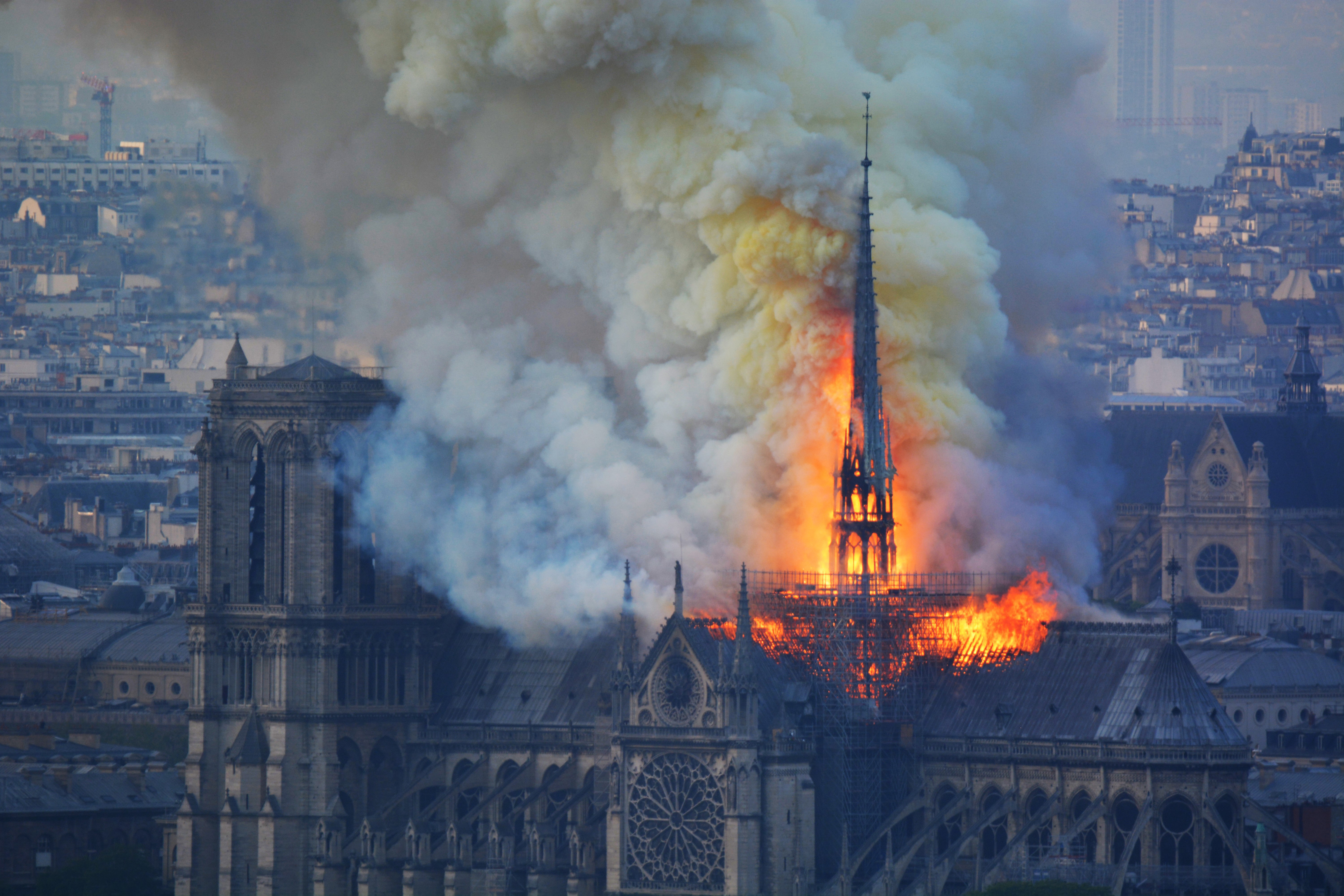 Smoke and flames rise during a fire at the landmark Notre-Dame Cathedral in central Paris on April 15, 2019, potentially involving renovation works being carried out at the site, the fire service said. - A major fire broke out at the landmark Notre-Dame Cathedral in central Paris sending flames and huge clouds of grey smoke billowing into the sky, the fire service said. The flames and smoke plumed from the spire and roof of the gothic cathedral, visited by millions of people a year, where renovations are currently underway. (Photo by Hubert Hitier / AFP)