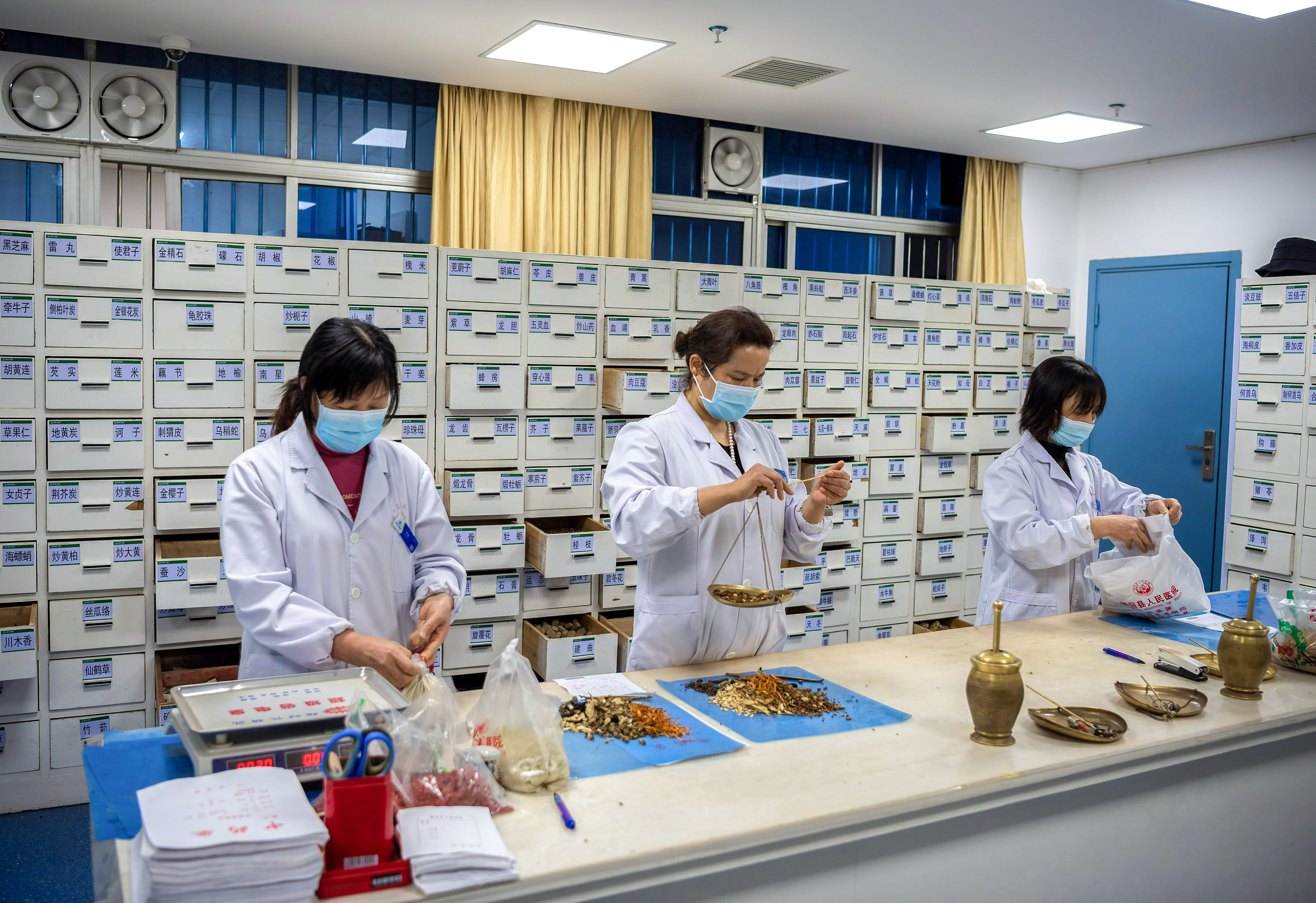Egészségügyi dolgozók készítik elő a hagyományos gyógykészítményeket egy jicsangi kórházban, Kína Hupej tartományában