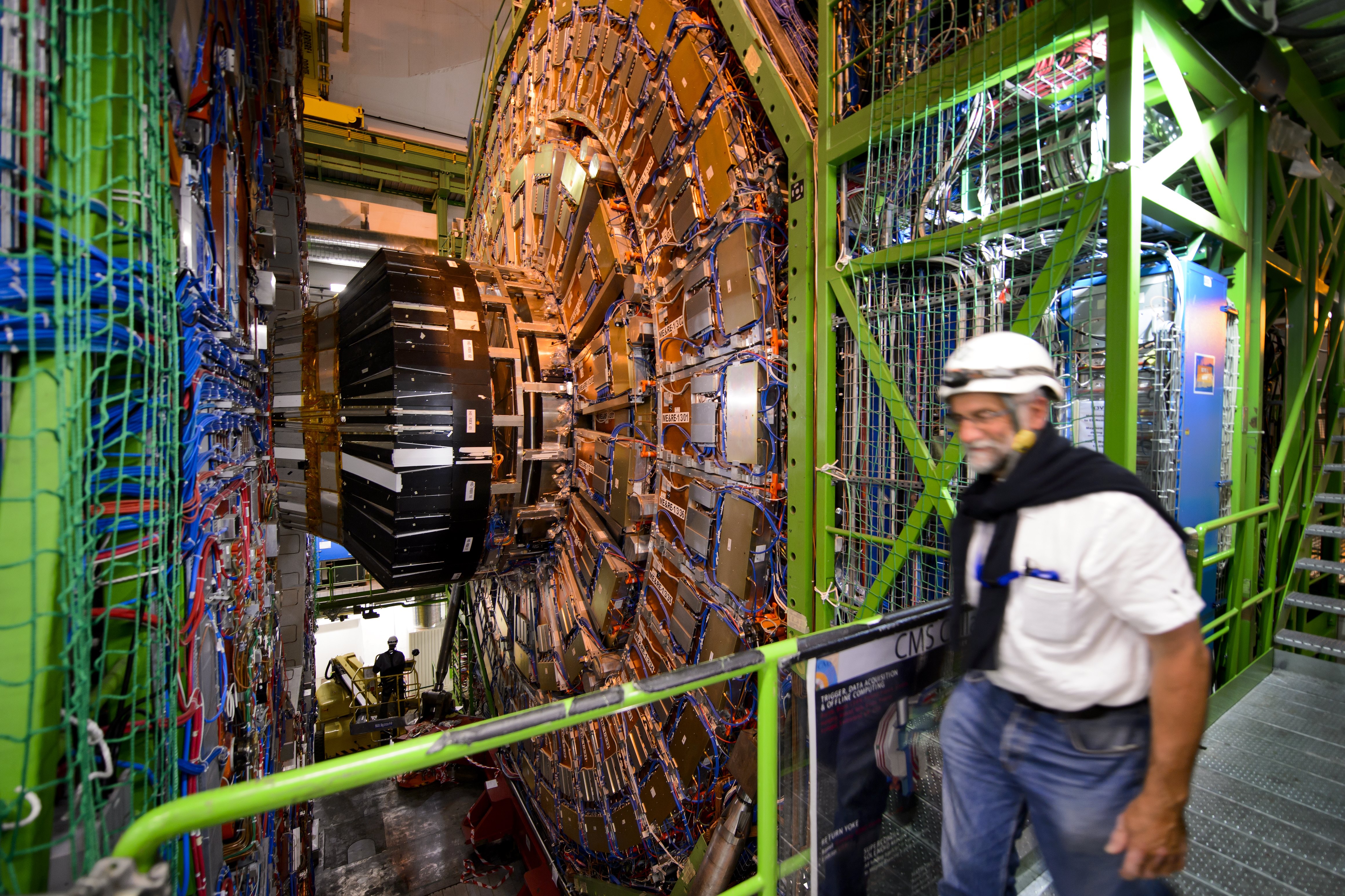 A Kompakt Müon Szolenoid (CMS) és egyik szerelője a Nagy Hadronütköztetőben (LHC) 2013 nyarán