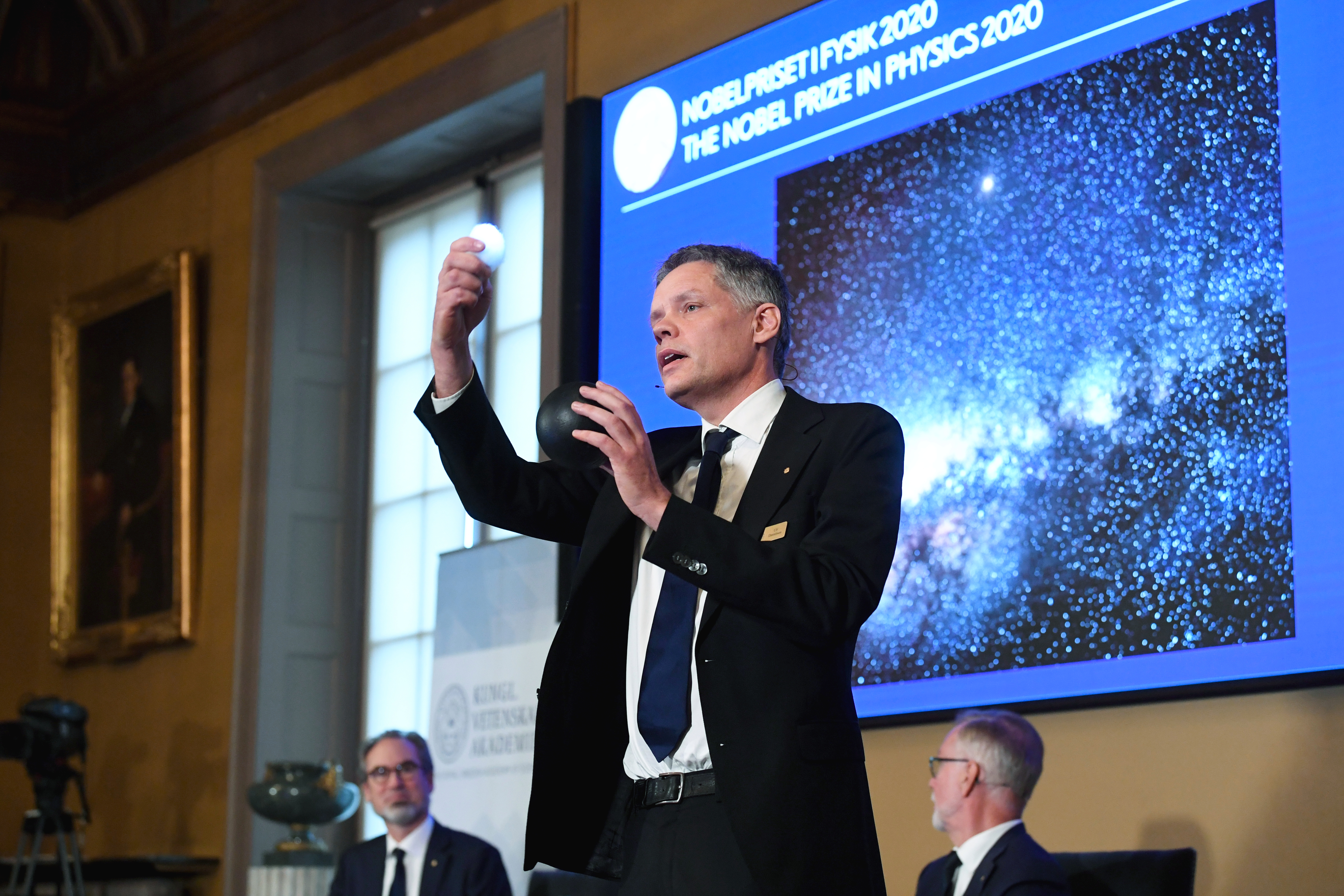 Ulf Danielsson, a Svéd Királyi Tudományos Akadémia csillagásza szemlélteti a fekete lyukak működését a 2020-as fizikai Nobel-díjak bejelentésén