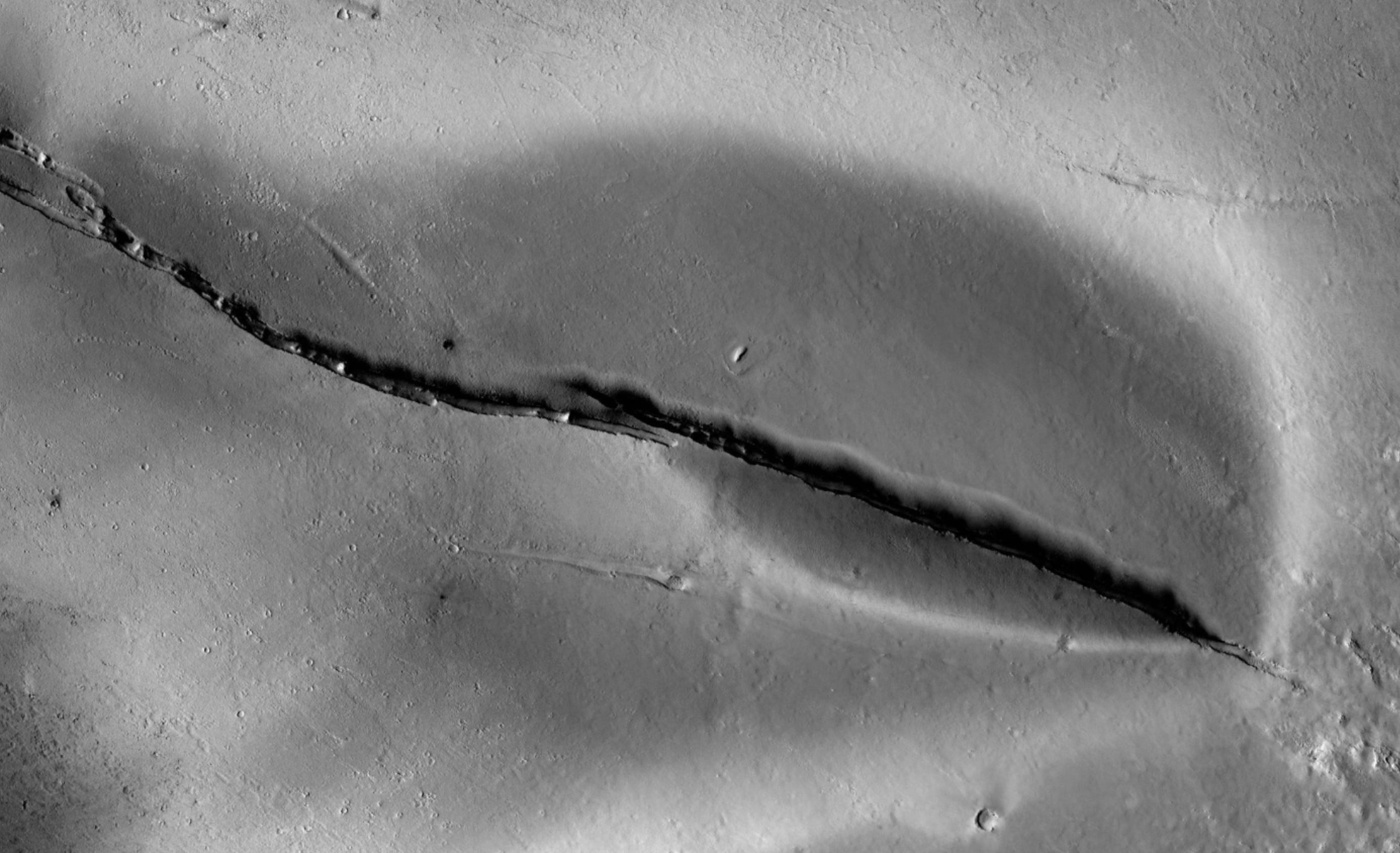 A Cerberus Fossae kérdéses területe, a környezeténél sötétebb, a hasadék két oldalán elhelyezkedő lerakódással, a Mars Reconnaissance Orbiter CTX kamerájának felvételén.