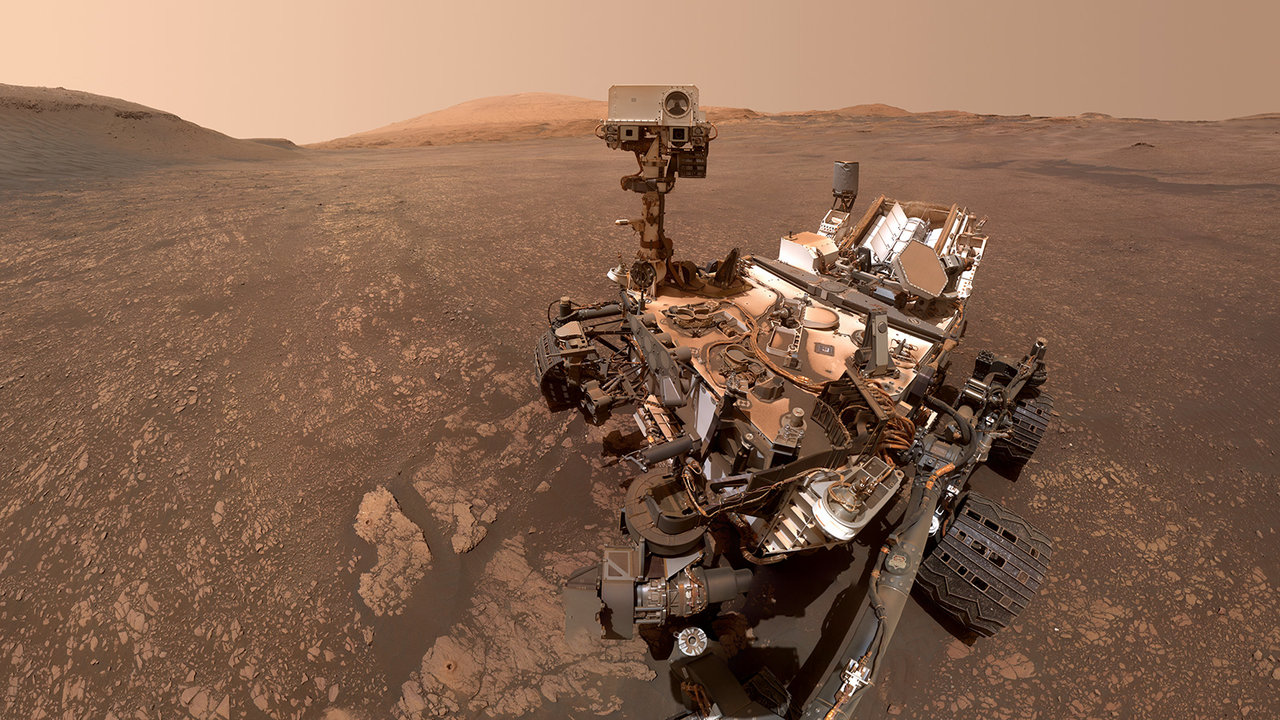 A Curiosity robotkarján lévő kamera által készített szelfin a marsjáró által vizsgált agyagos-réteg és két friss fúrásminta látható.