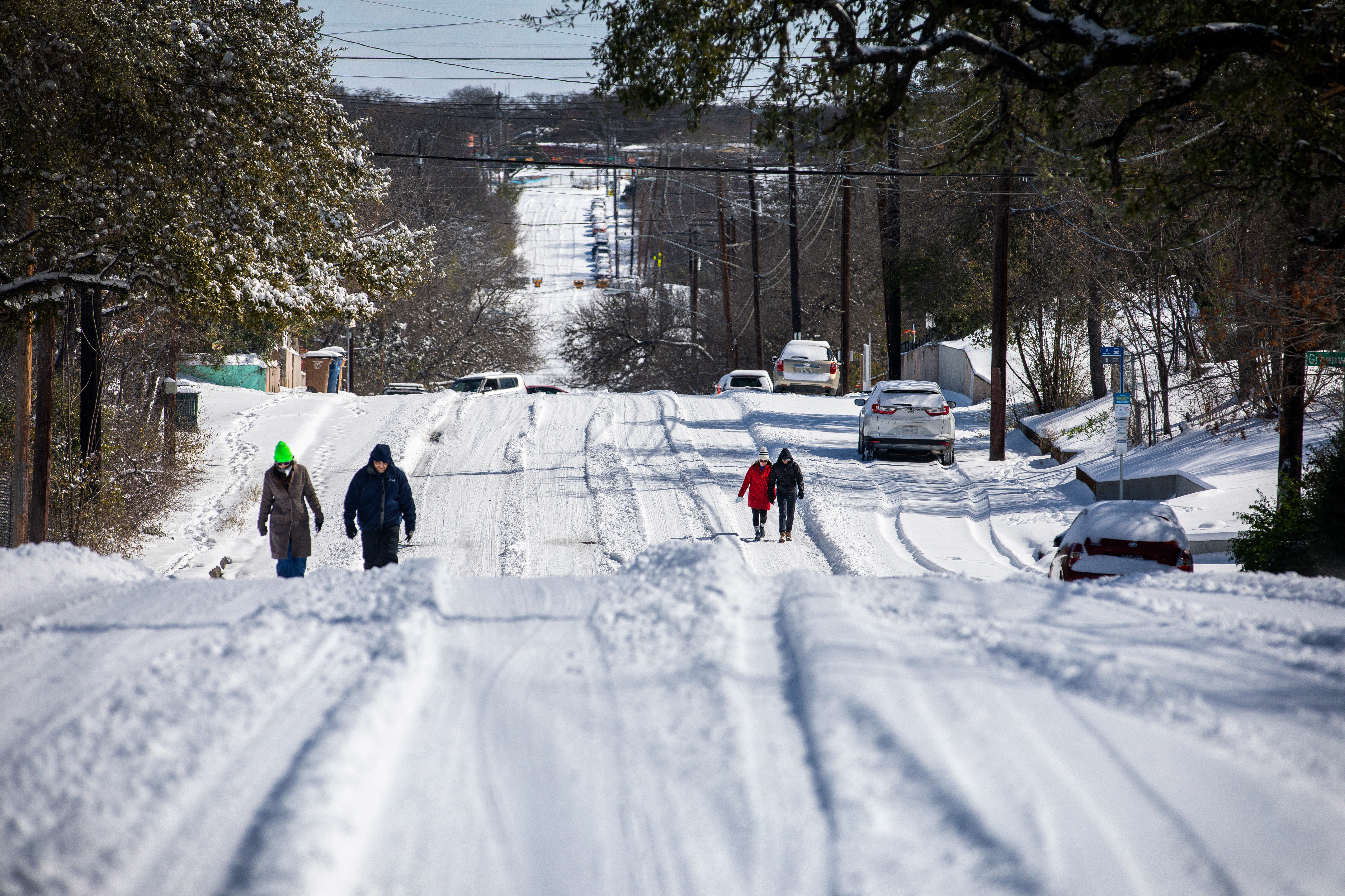 Gyalogosok sétálnak egy jeges úton 2021. február 15-én a texasi Kelet-Austinban. Az Uri téli vihar rekordhideg időjárást hozott Texasba, ami forgalmi késéseket és áramkimaradásokat okozott, a viharok pedig 26 államon söpörtek végig, fagyos széllel és sok csapadékkal.
