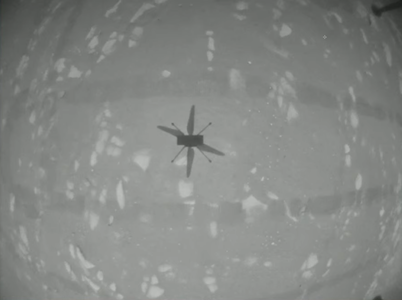 Az Ingenuity helikopter lefele tekintő kamerájának felvétele az első repülés egy pillanatát örökíti meg.