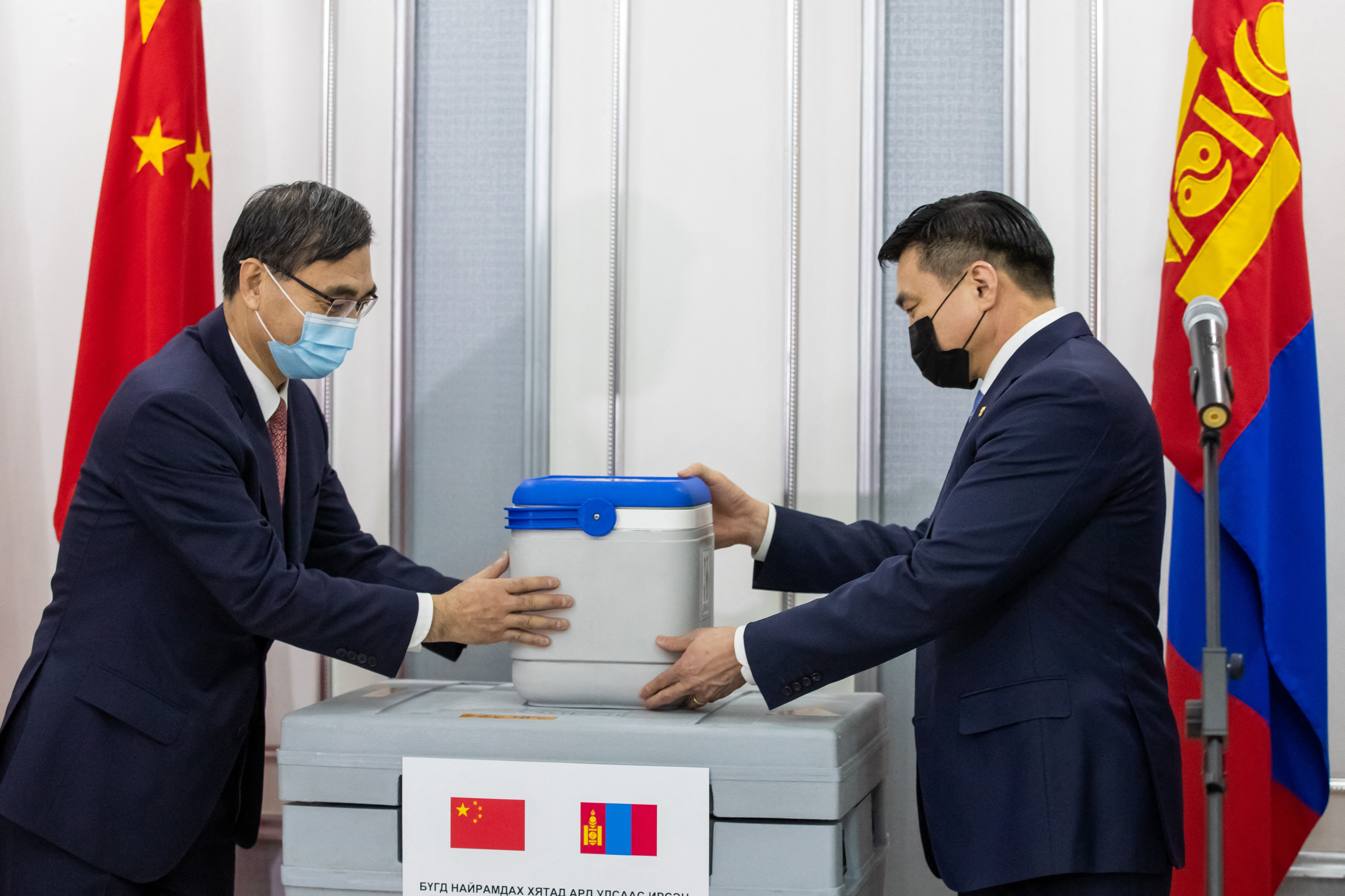 Kína mongóliai nagykövete egy doboz Sinopharm-vakcinát nyújt át a mongol miniszterelnök-helyettesnek, 2021 februárjában, Ulánbátorban