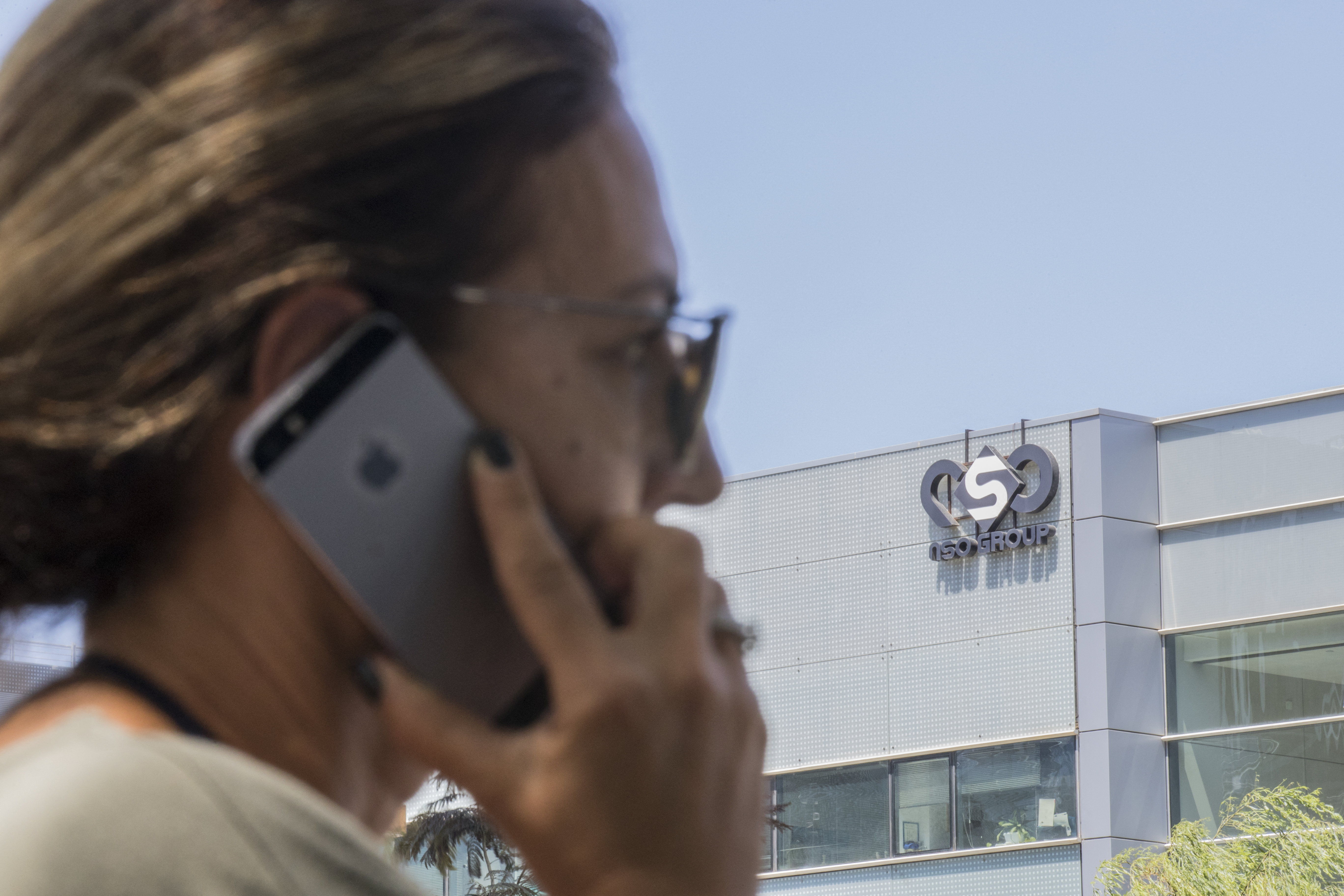 Mobiltelefonáló nő az izraeli NSO Group, a Pegasus kémszoftver üzemeltetőjének herzliyai székháza előtt Izraelben.