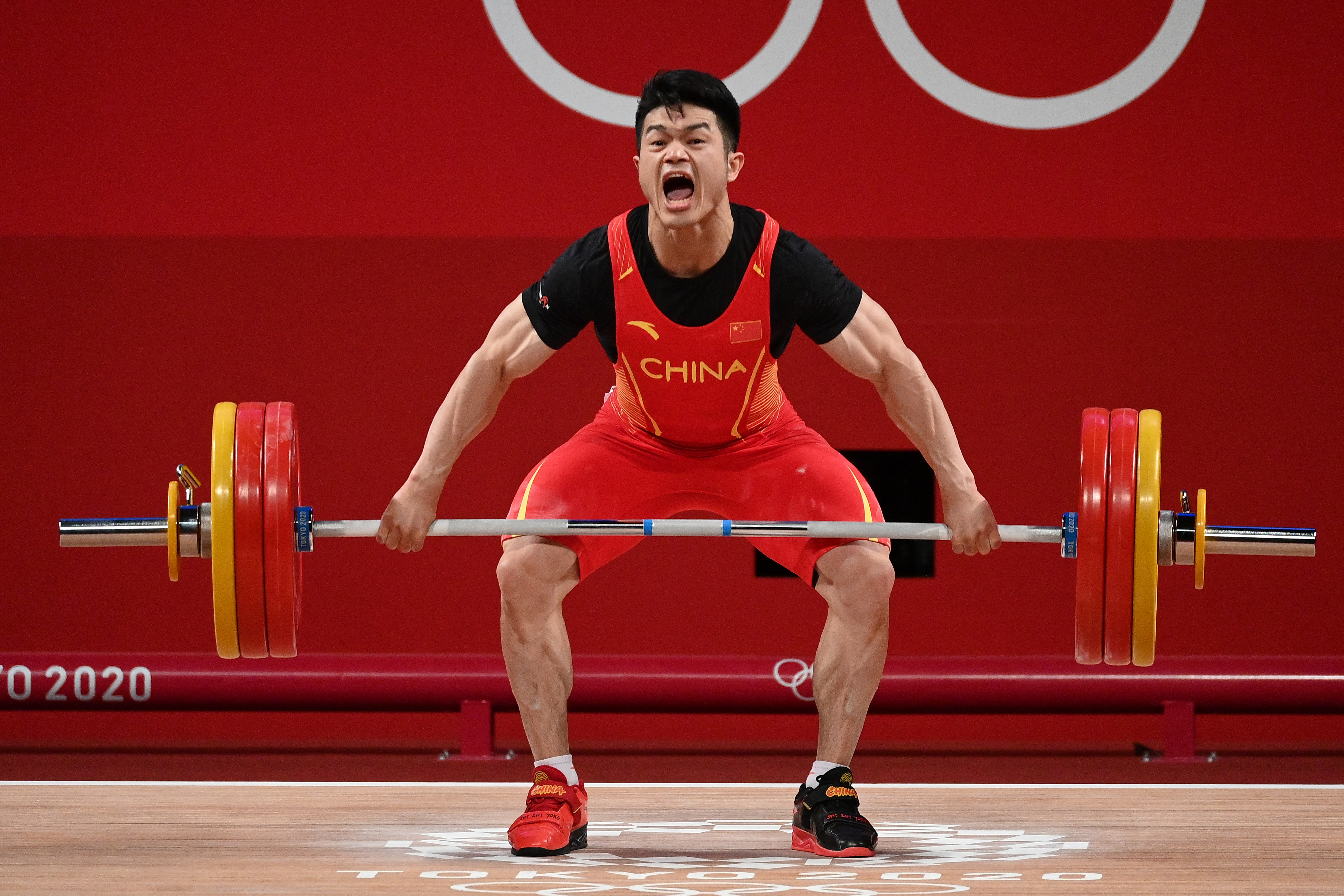 A férfiak 73 kilogrammos súlycsoportjában világcsúccsal aranyérmes kínai Si Cse-jung a 3D-nyomtatással készült cipőkban és mezben július 28-án a tokiói olimpián