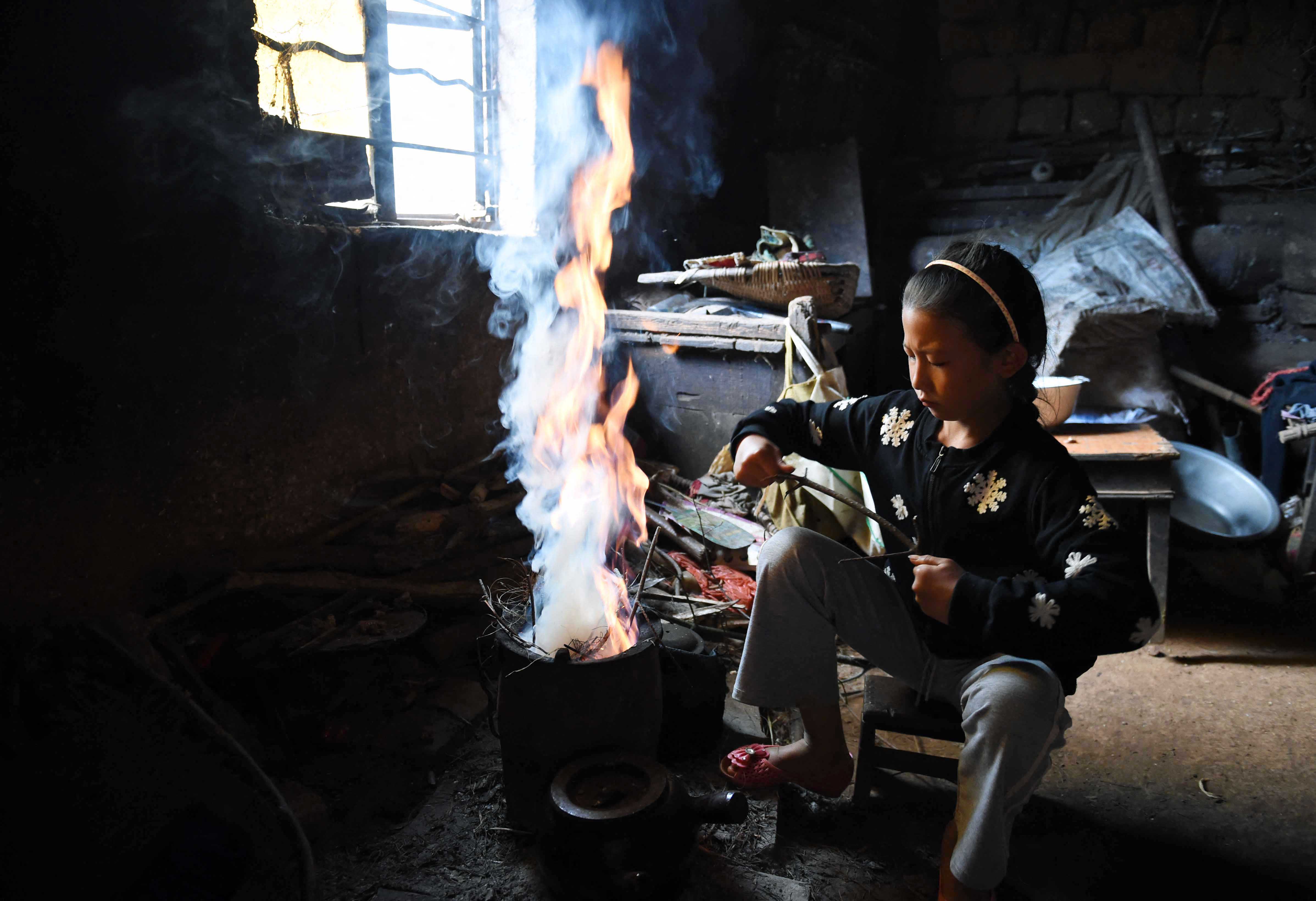 A 10 éves He Jüan-hszi ételt készít otthon a délnyugat-kínai Jünnan tartománybeli falujában 2016-ban.