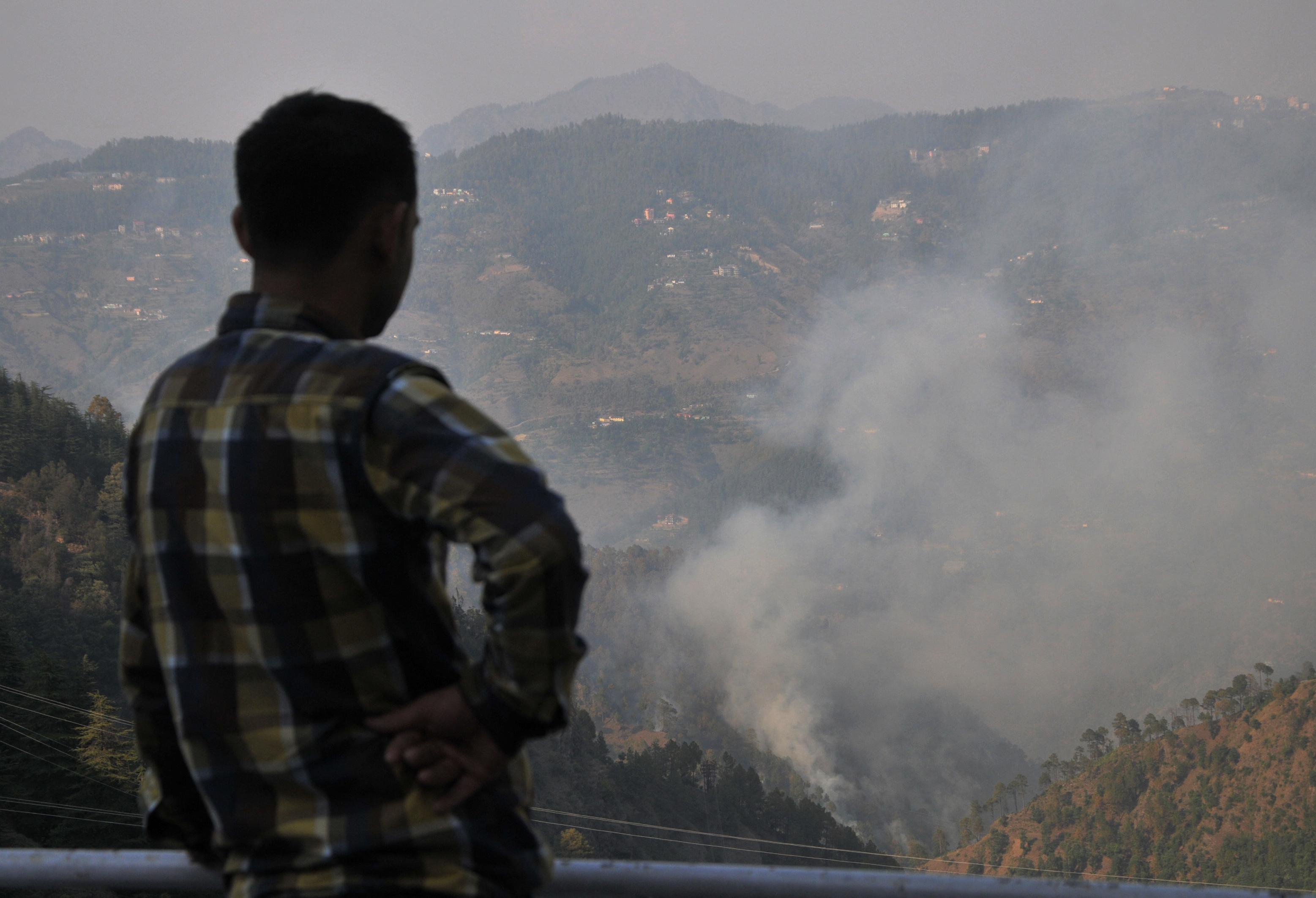 Egy helyi lakos nézi az erdőtüzet az indiai Himacsál Prades államban fekvő Simla közelében 2016. május 2-án. A tűz több mint 1900 hektárnyi erdőt érintett, és két ember életét követelte. Helikopterekkel és több ezer lakos segítségével igyekeztek eloltani a lángokat.