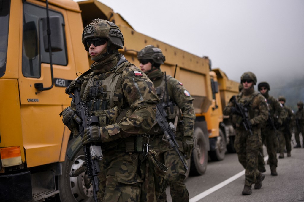 A KFOR katonái a szerbek által dömperekből emelt útblokád mellett járőröznek Koszovó északi határánál 2021. október 2-án.