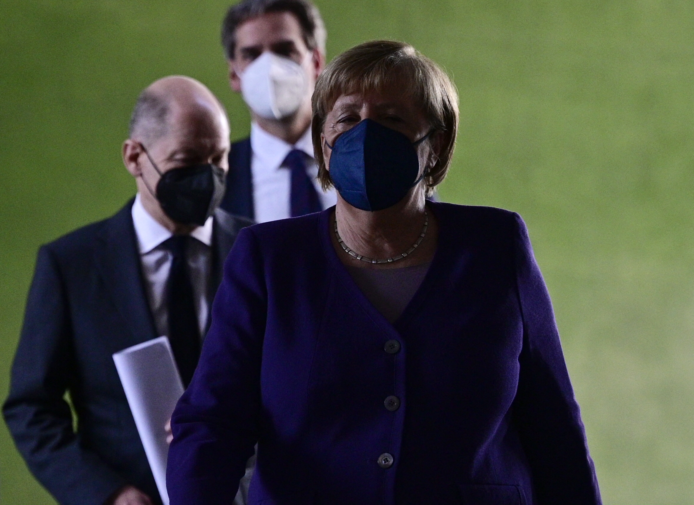 Angela Merkel leköszönő kancellár érkezik a sajtótájékoztatóra, mögötte utódja, Olaf Scholz követi