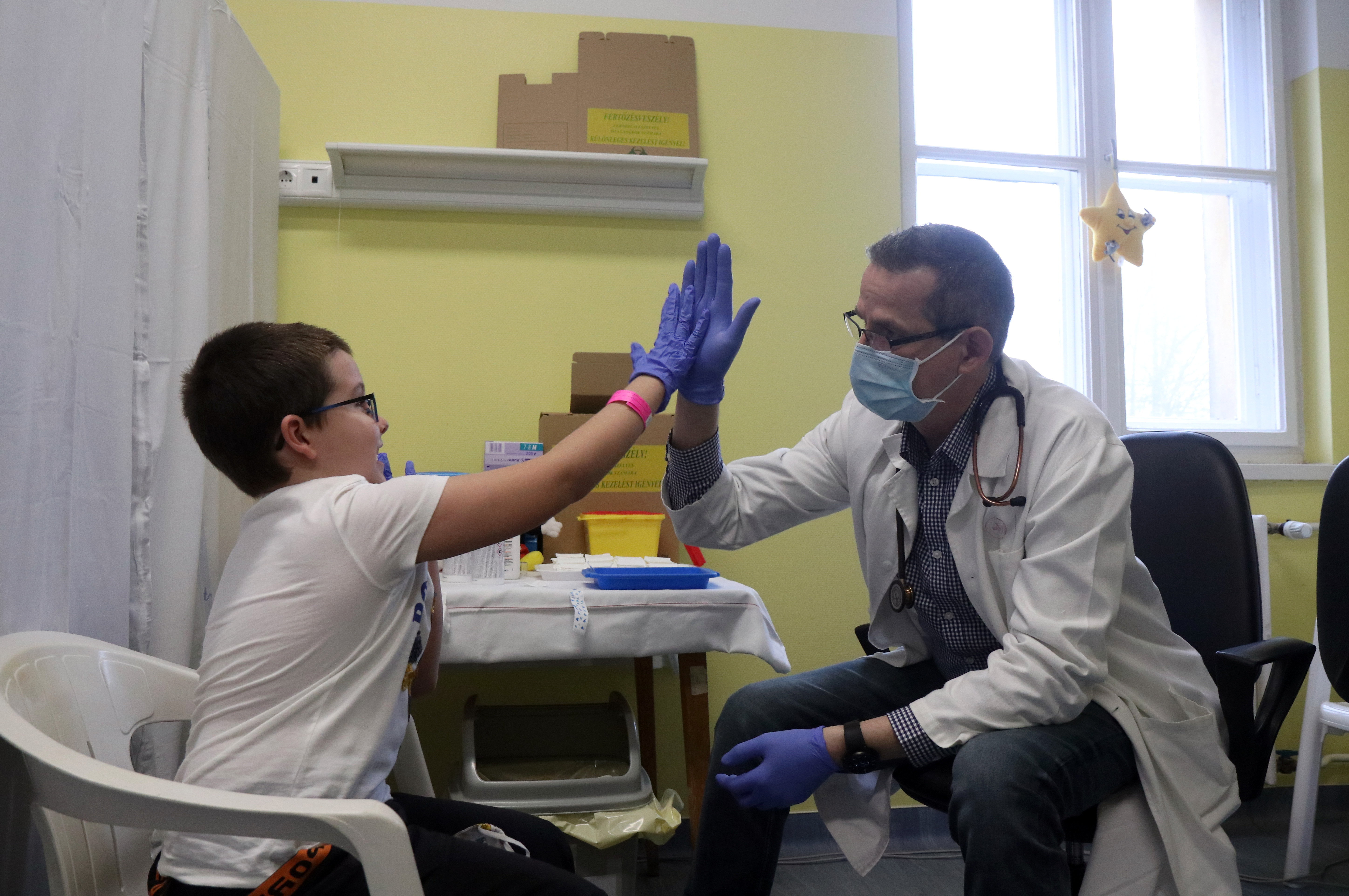 Egy fiú pacsizik az orvossal, miután beoltották a Pfizer-BioNTech koronavírus elleni oltóanyagának gyerekek oltására alkalmas változatával Miskolcon 2021. december 19-én