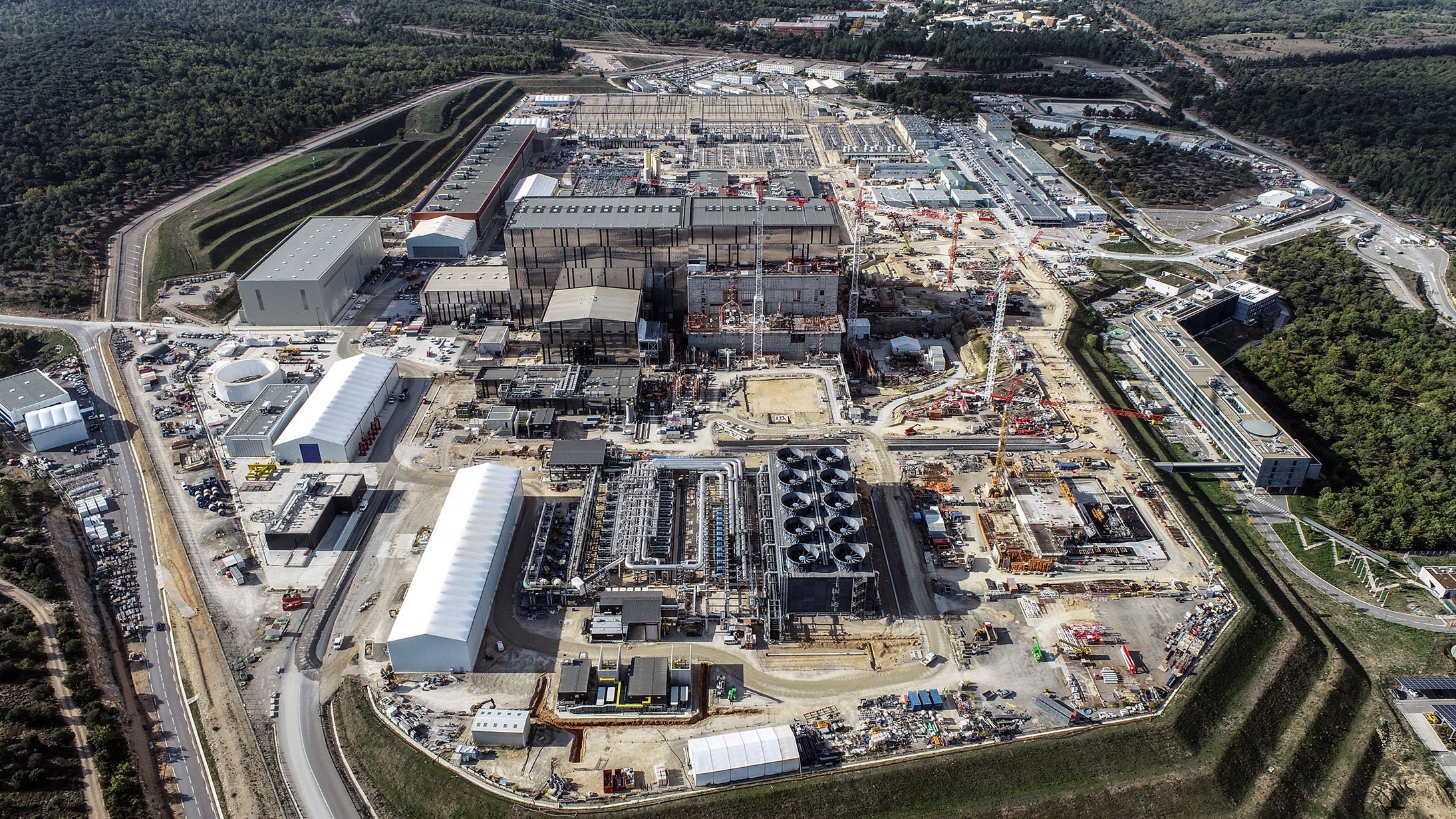 A franciaországi ITER kísérleti fúziós reaktor egy 2021 októberi felvételen. A tokamak a nagy középső épületek jobboldali szárnyában található