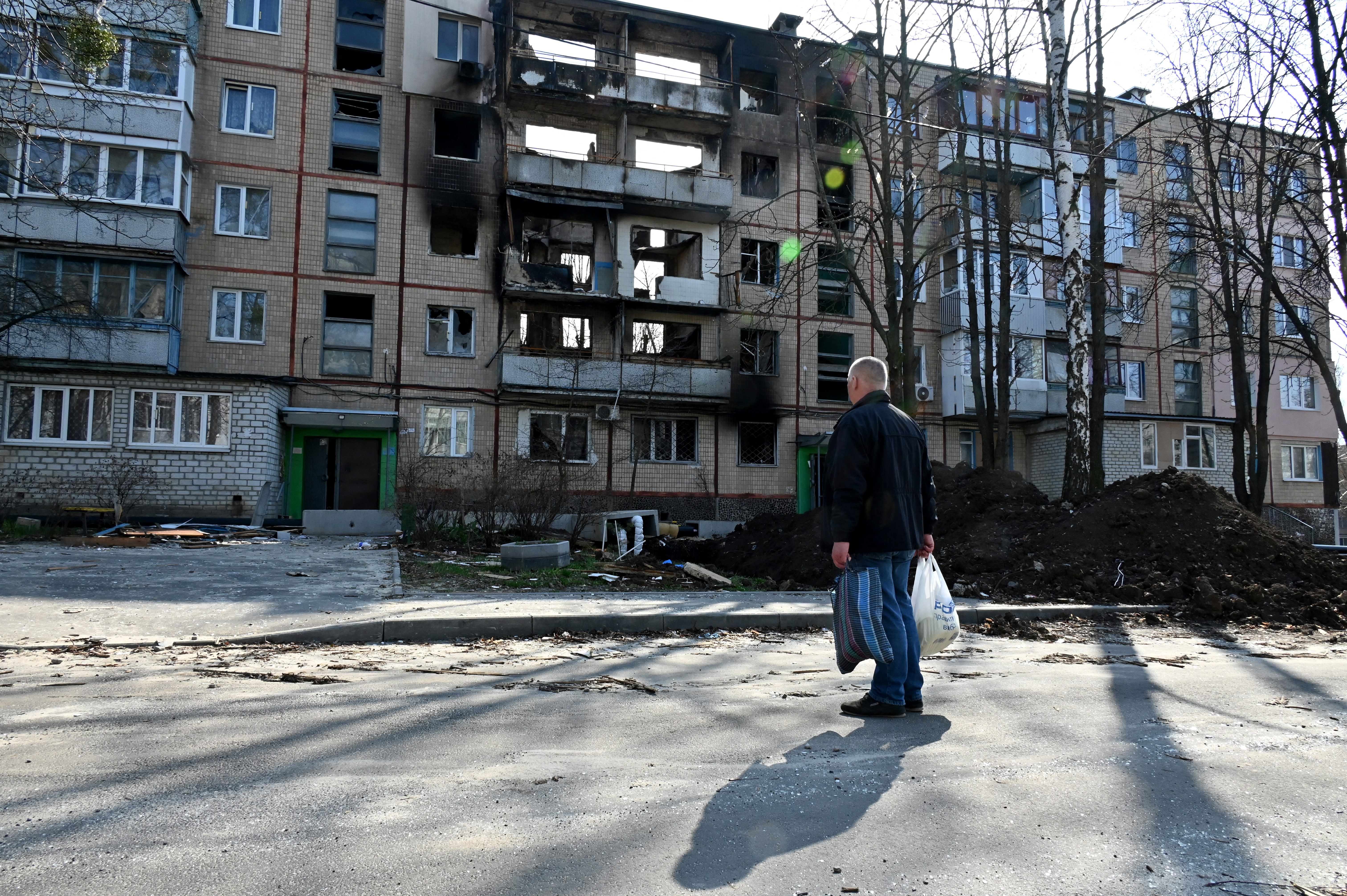 Egy harkivi férfi szemlél egy lebombázott lakótelepi házat.