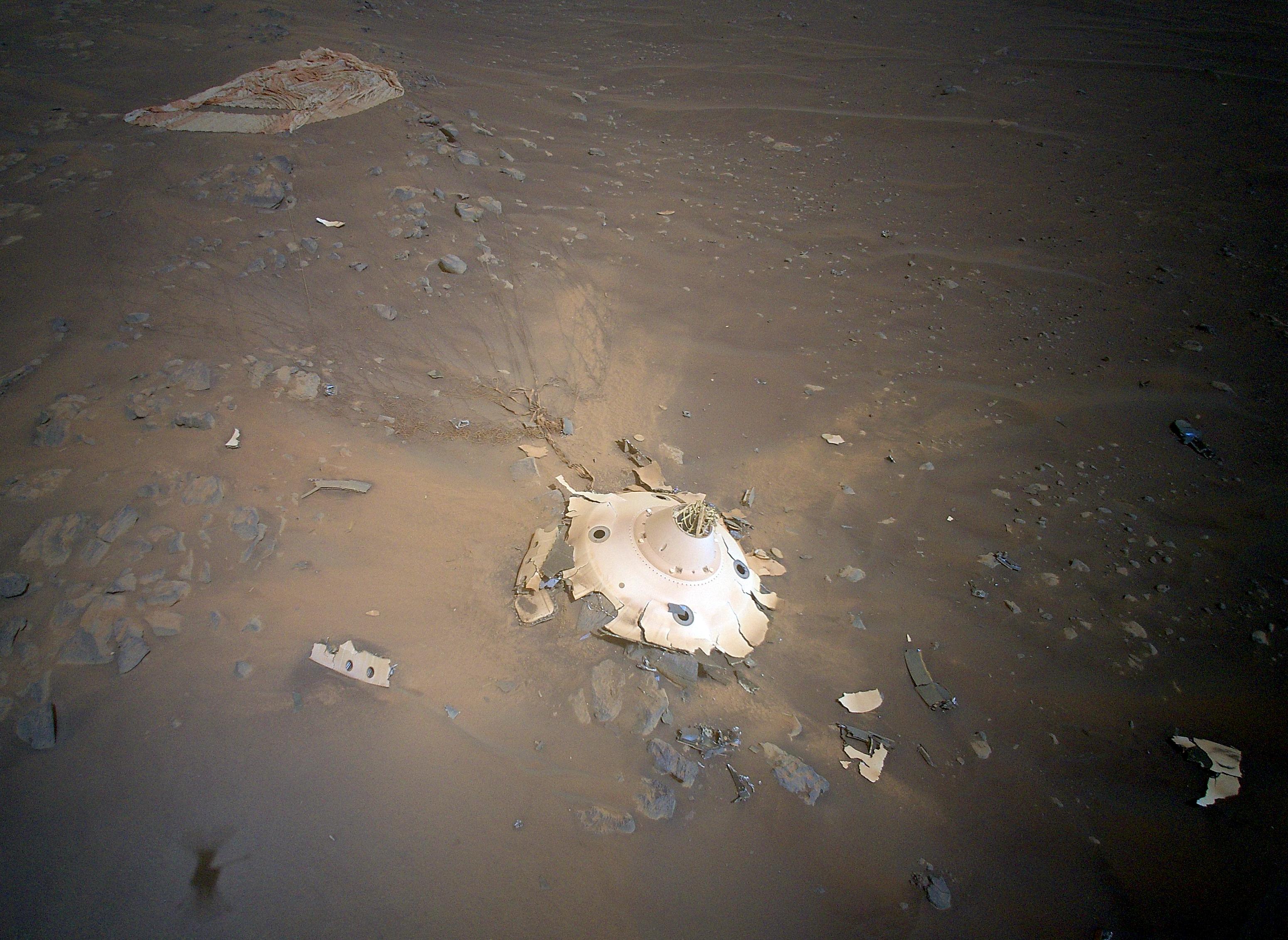 A Perseverancet és az Ingenuityt Marsra szállító kapszula hátuljának (középen lent) maradványai és a szuperszonikus ejtőernyő (bal fent) a Mars-helikopter felvételén
