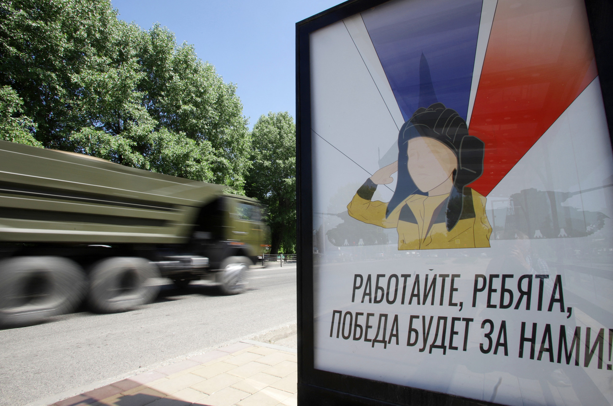 Egy belgorodi plakát az orosz médiában sztárrá váló nyolcéves kisfiúval, aki minden nap kiállt az út szélére köszönteni az Ukrajna felé tartó tankokat