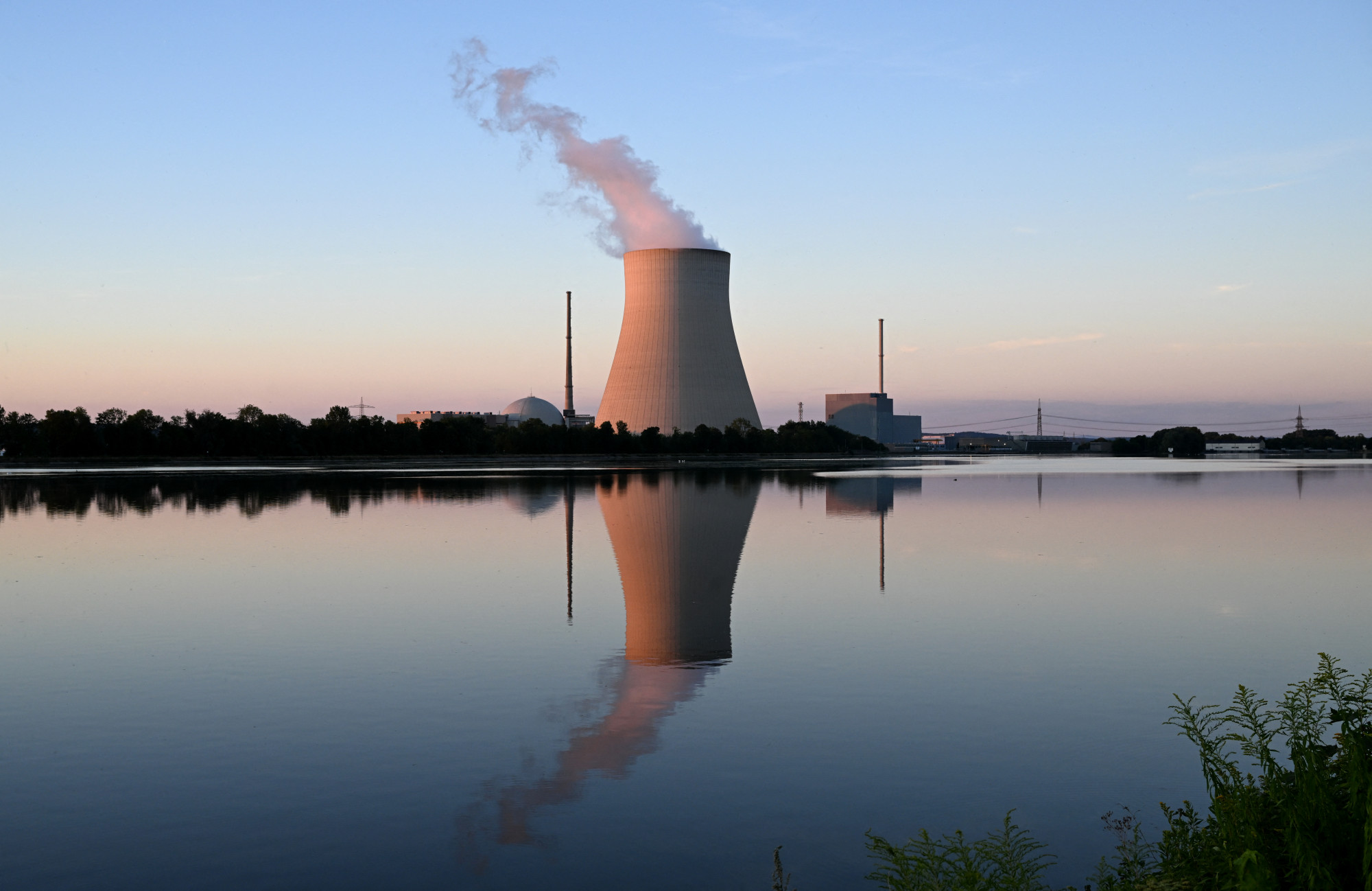 Az Isar atomerőmű hűtőtornya az Isar folyóban tükröződik a dél-németországi Landshut melletti Essenbachban 2022. augusztus 3-án.