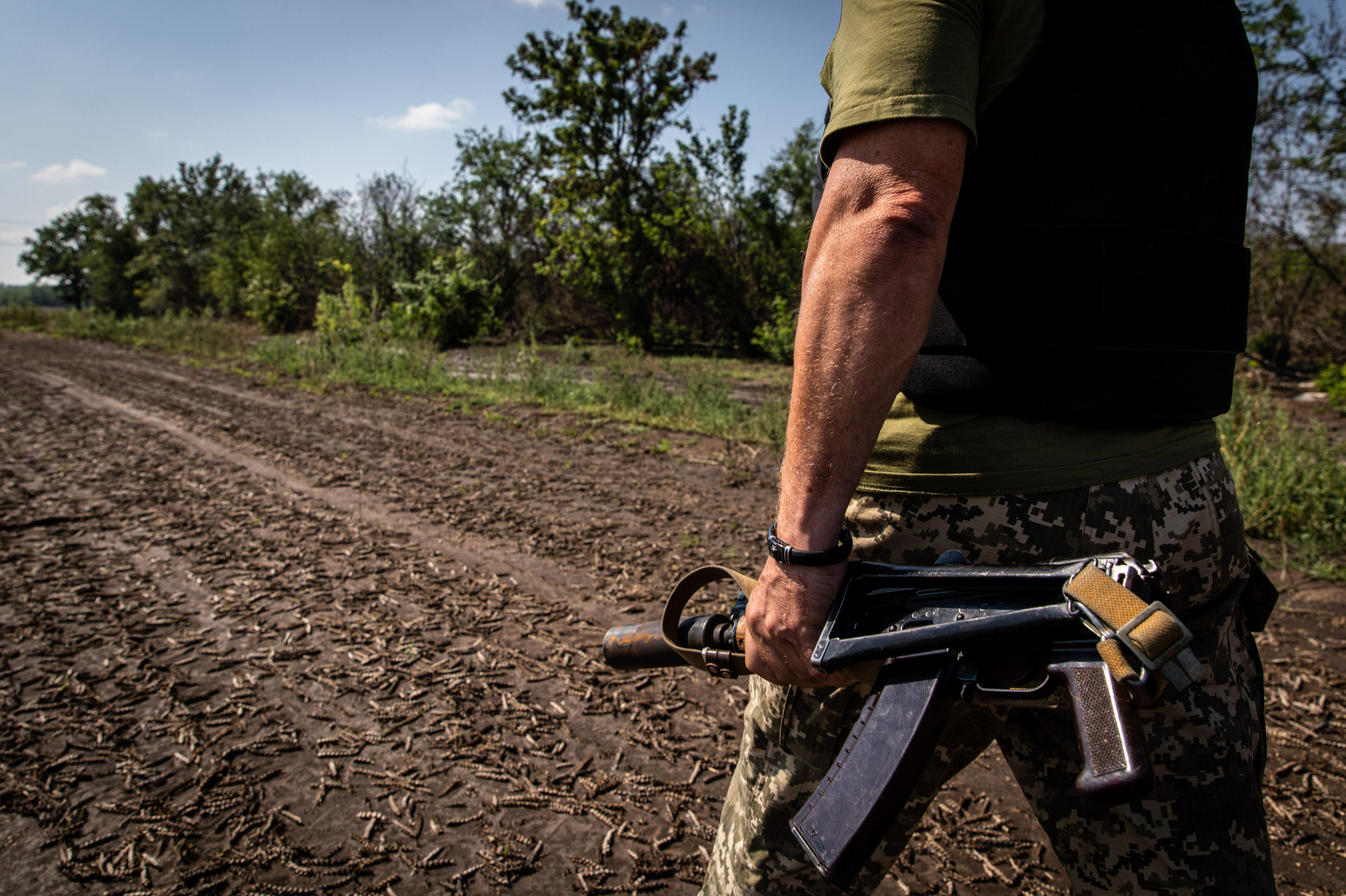 Szerhij, az ukrán katona összehajtott AKS gépkarabélyával a frontvonalhoz közeli mezőn sétál Mikolajiv megyében.