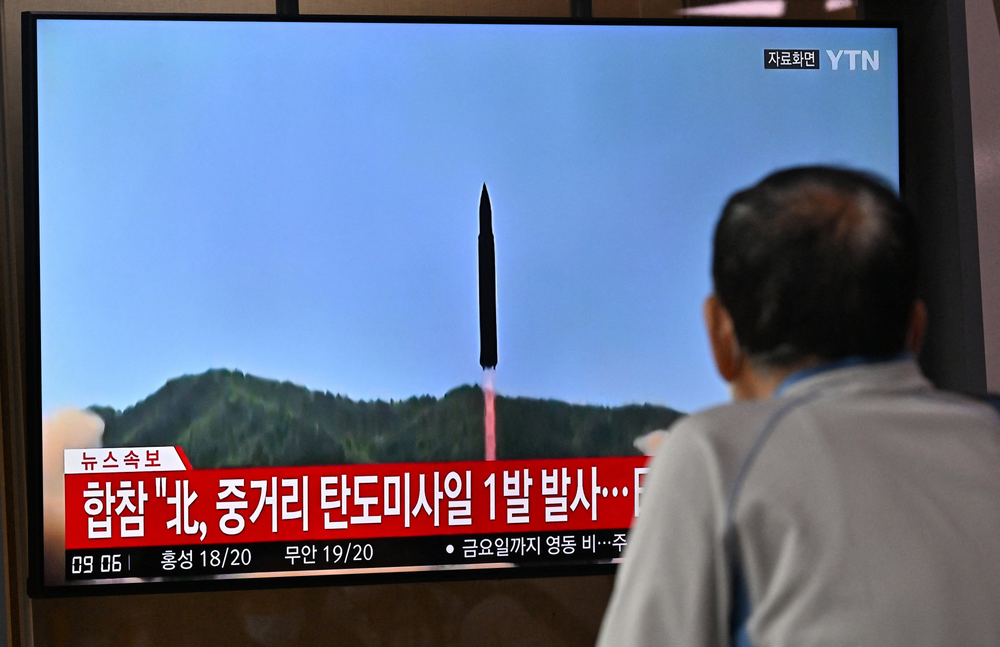 Japán polgár nézi feszülten a híreket, amiben éppen egy észak-koreai rakétakísérlet képeit mutatják.