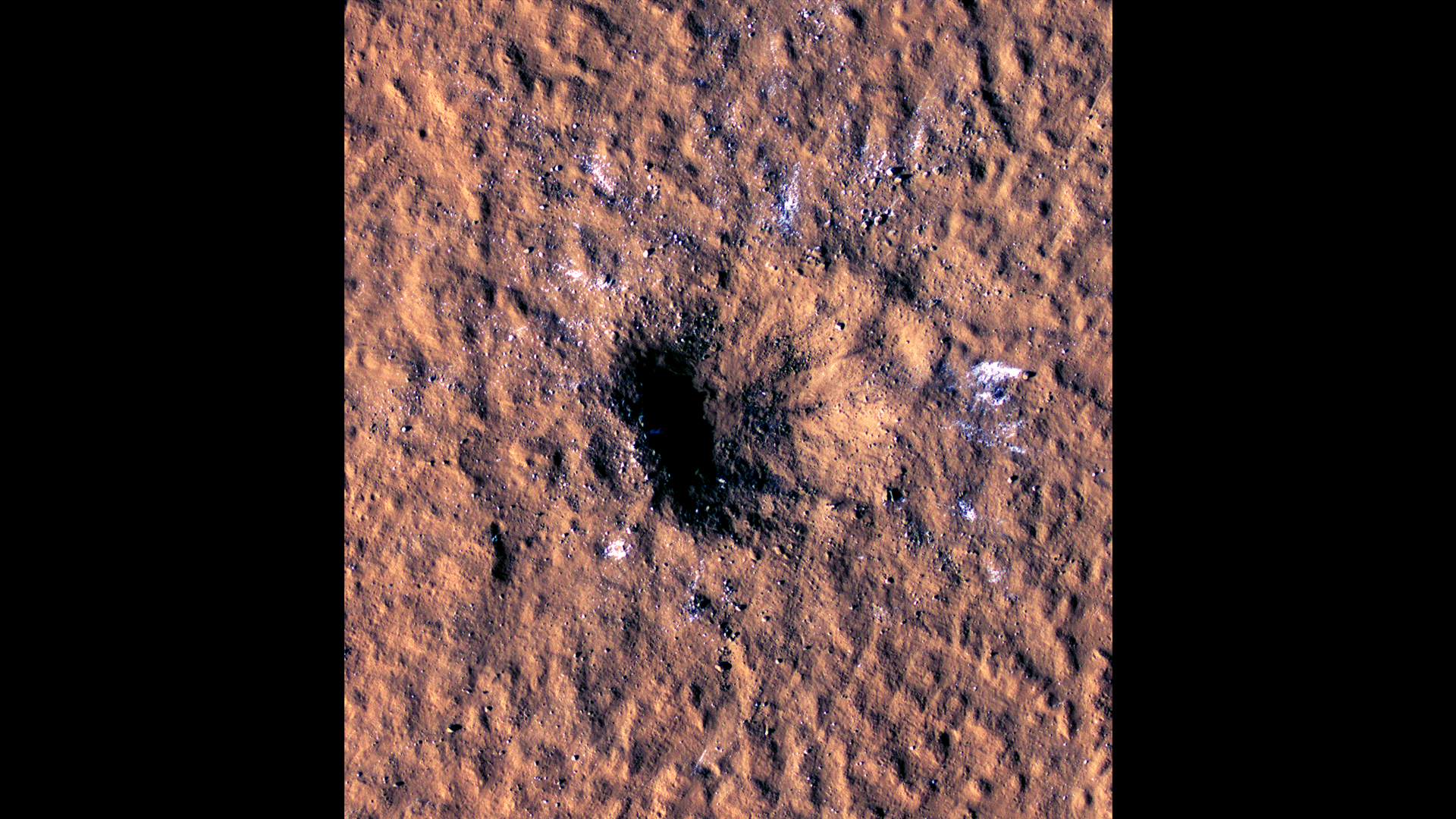 A Mars Reconnaissance Orbiter HiRISE kamerájának felvétele a 150 méteres átmérőjű, 2021 decemberében keletkezett kráterről. A világos foltokban vízjég található, amit a becsapódás a felszín alól vájt ki.