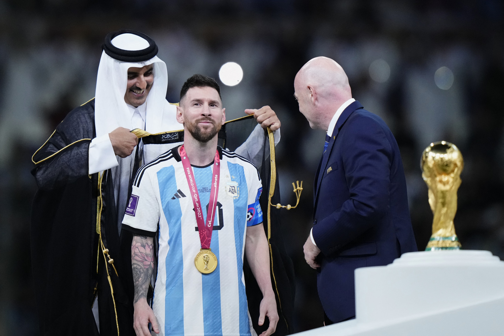Tamím emír egy köpenyt ad Messire, a jelenetet Gianni Infantino FIFA-elnök szemléli
