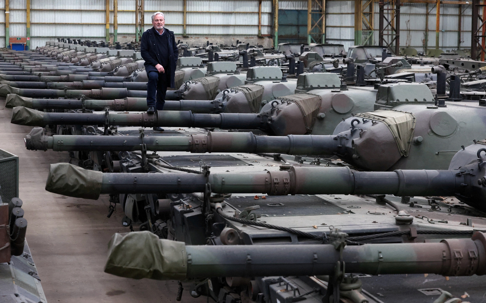 Lezsírozott Leopard 1-es nehézpáncélosok a belga OIP Land Systems fegyverkereskedő cég tournais-i raktárában. A képen az OIP vezérigazgatója, Freddy Versluys egyensúlyozik, ő januárban kért engedélyt a vallon és a német kormánytól, hogy exportálhassa páncélosait Ukrajnába.